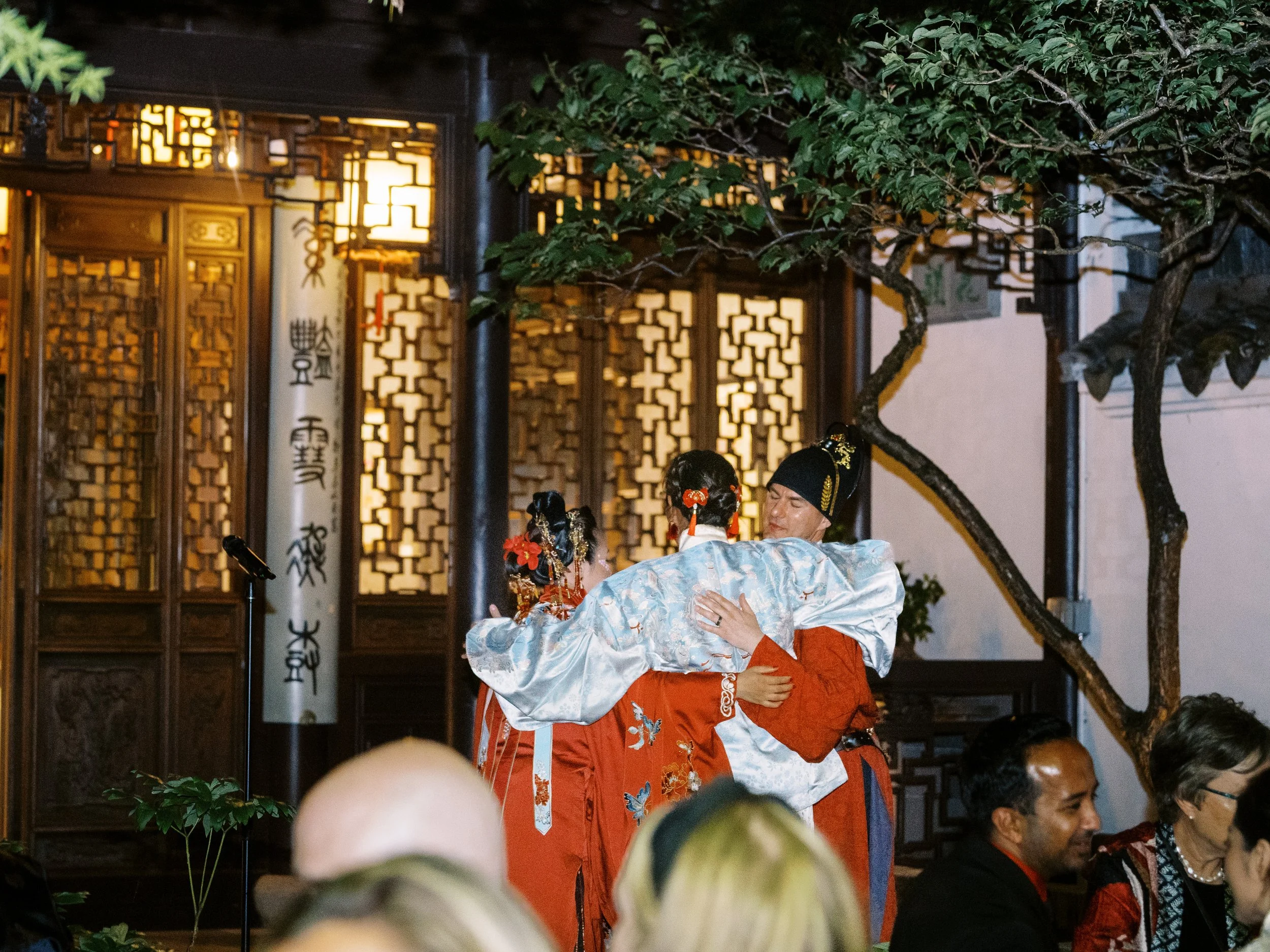 Friends hugging during an intimate evening reception at Lan Su Chinese Garden in Portland.