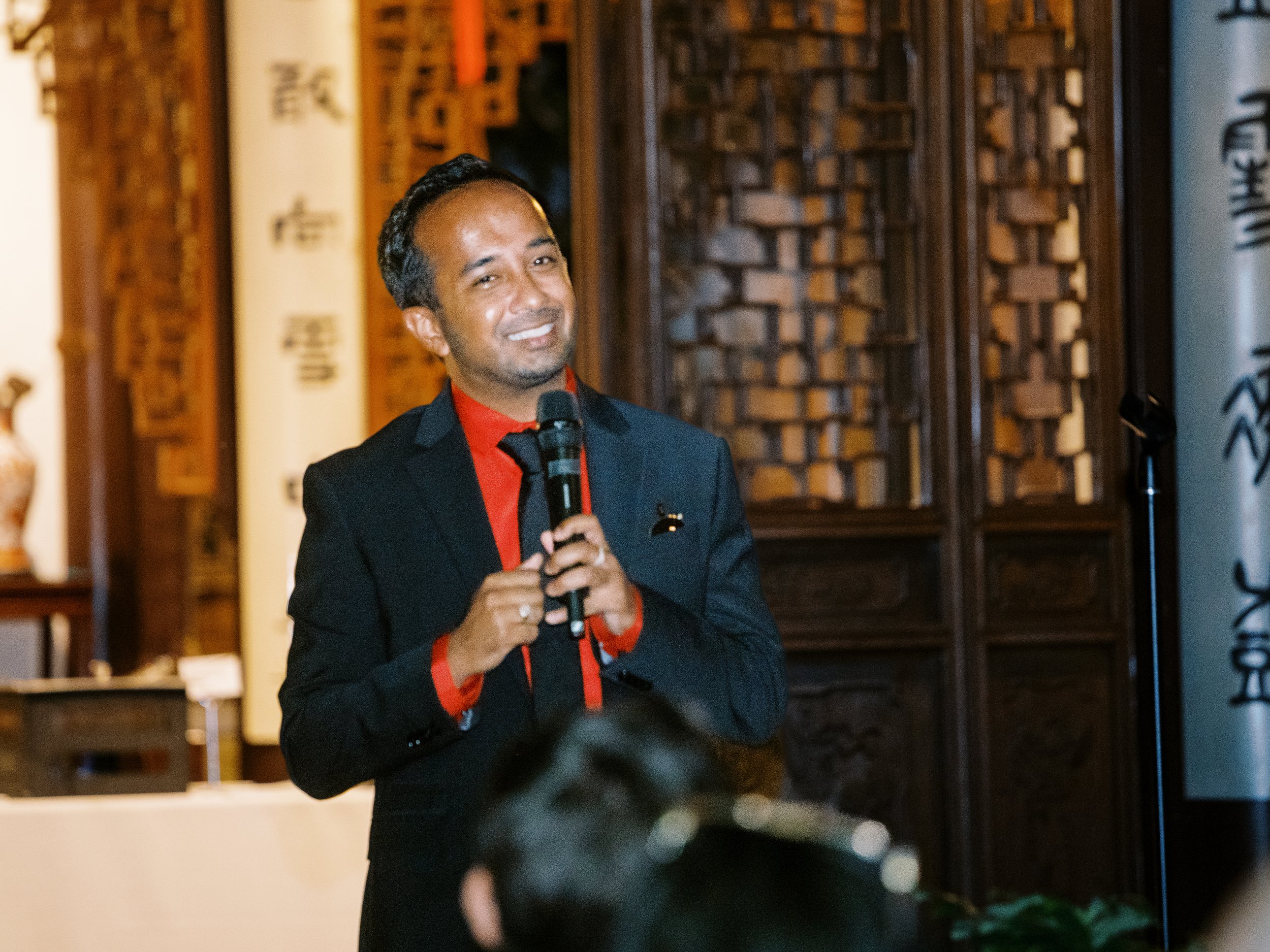 Wedding guest giving a toast during an evening reception at Lan Su Chinese Garden.