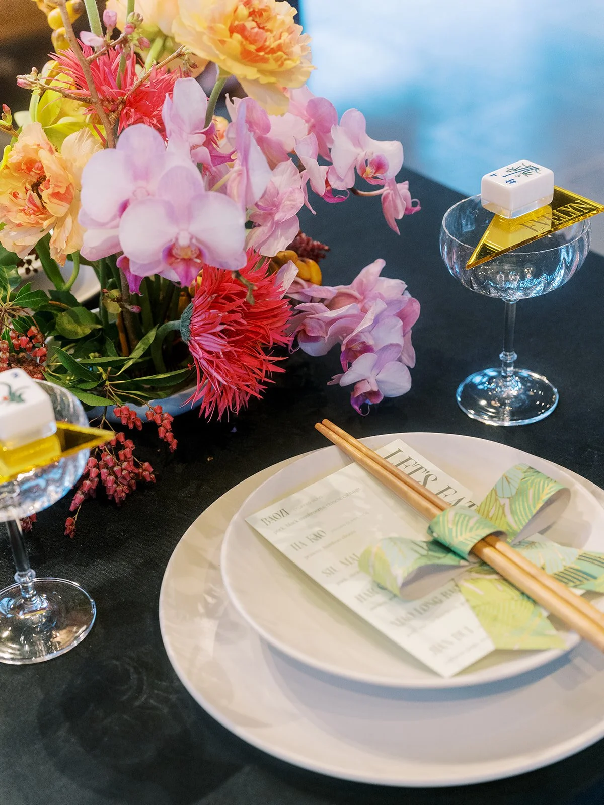 Detail of a styled bachelorette table featuring dim sum menus, floral arrangements in a cultural celebration setting.