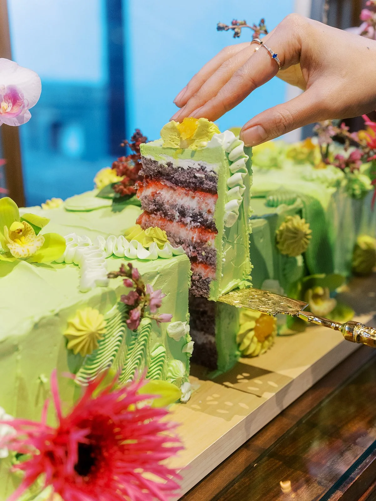 Hand cutting into a custom green floral cake during a culture inspired bachelorette celebration at Lan Su Chinese Garden.