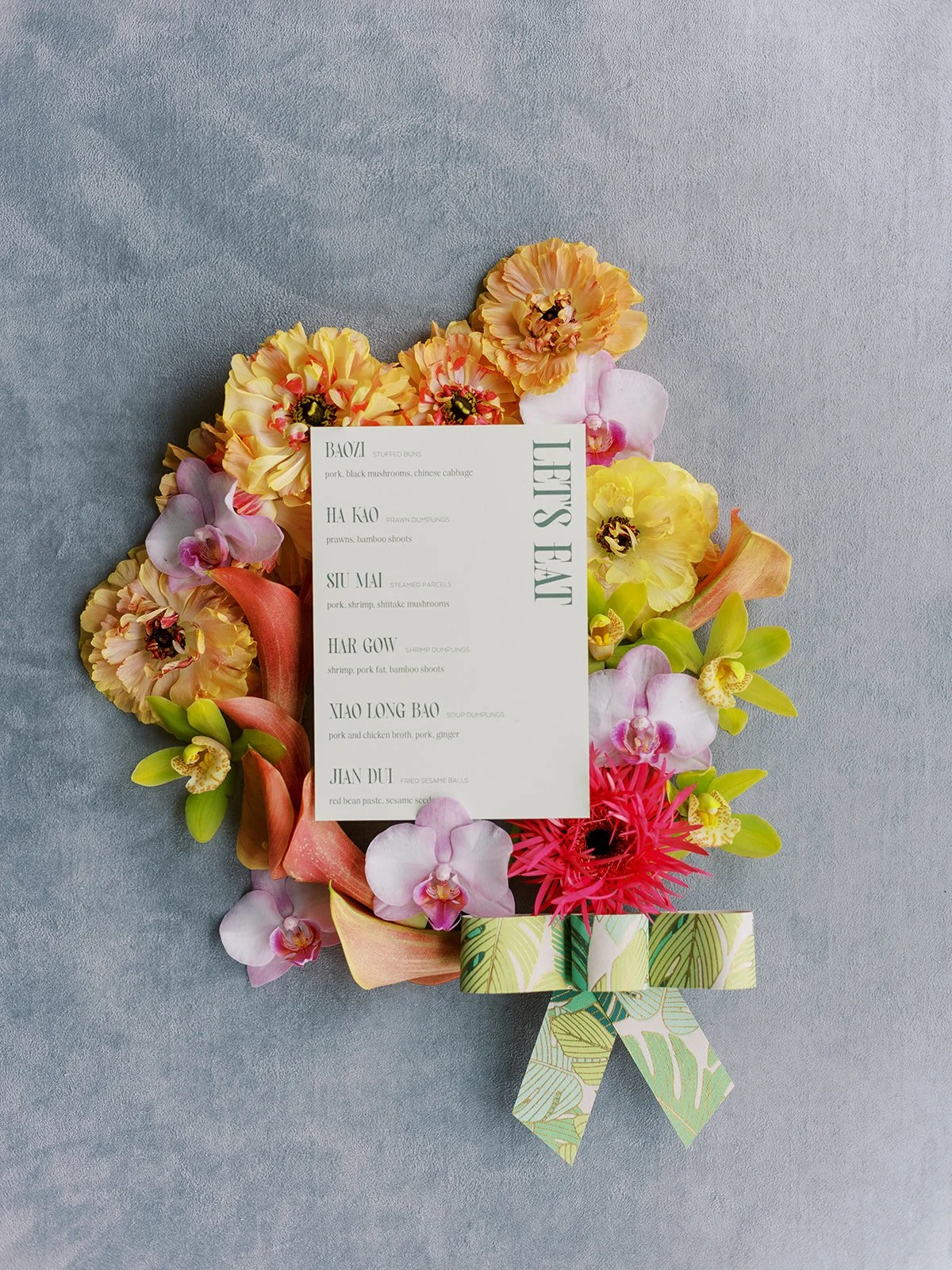 Dim sum menu surrounded by colorful florals styled for a couture bachelorette party inspired by Chinese garden aesthetics.