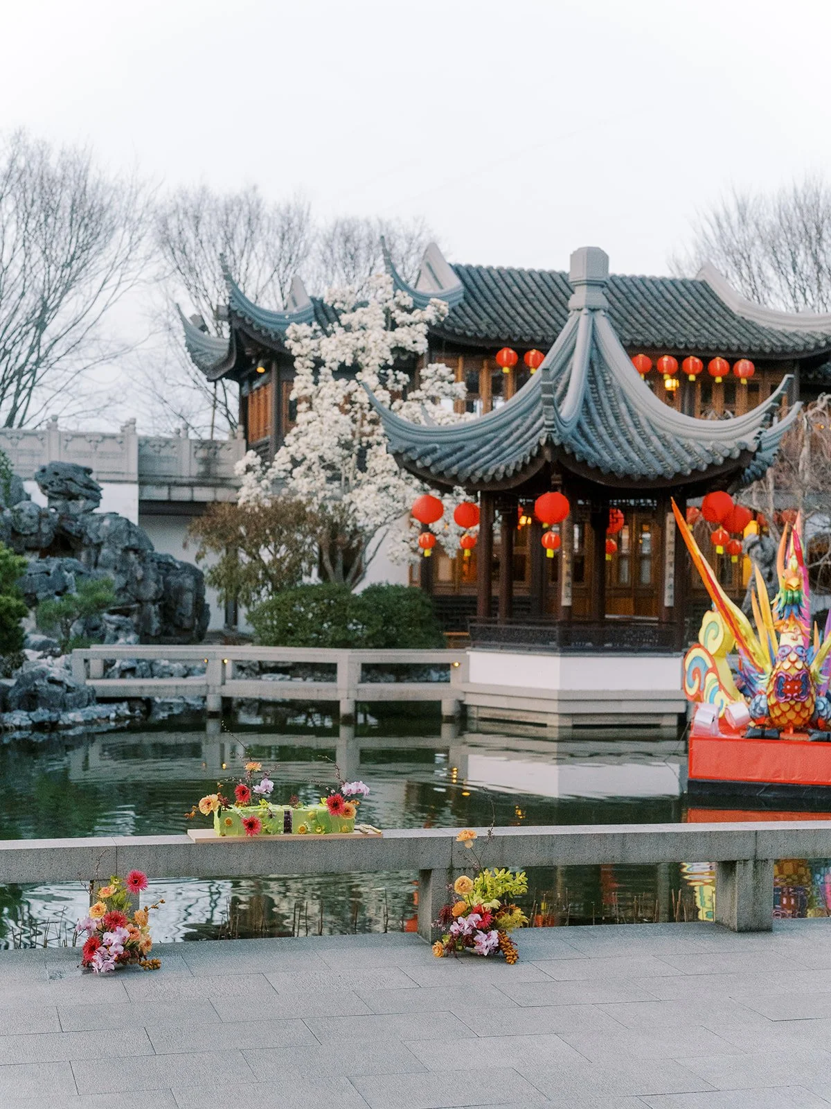 Lan Su Chinese Garden pavilion with red lanterns reflected in the koi pond, styled for an elegant bachelorette celebration.