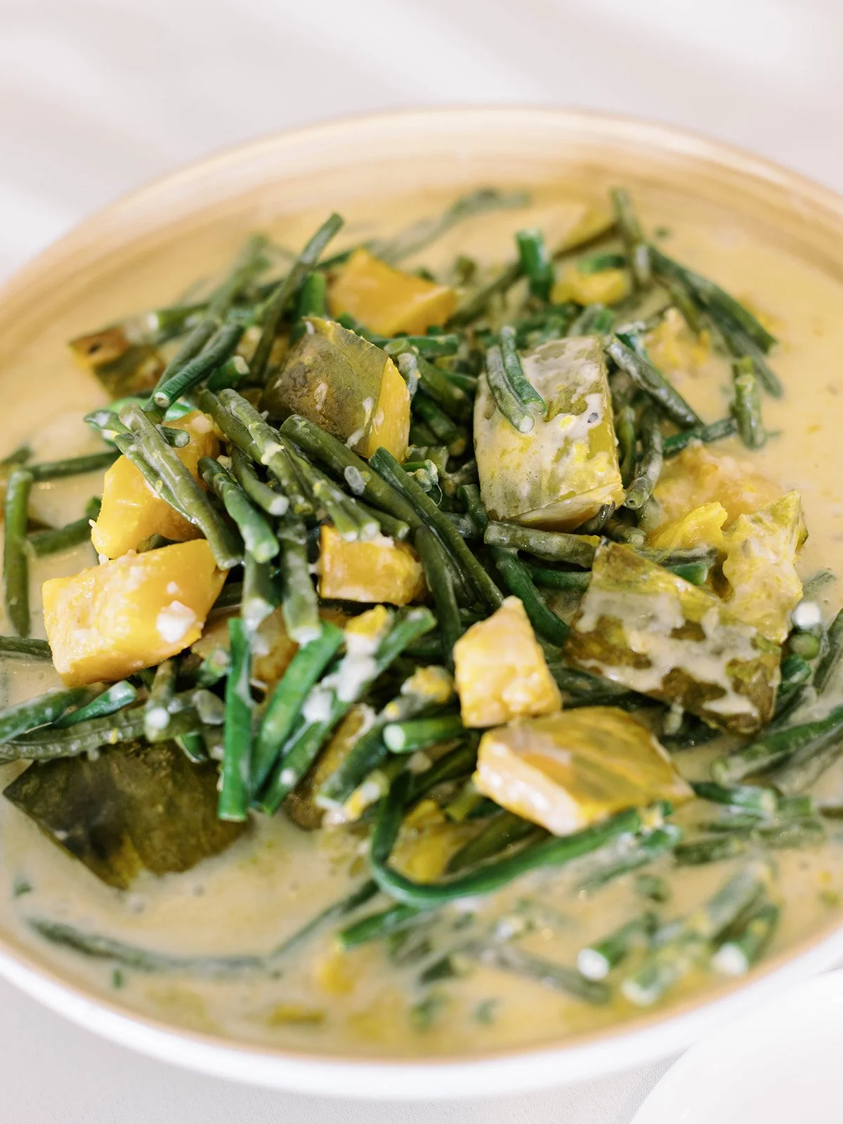 Close-up of a Filipino vegetable dish served in coconut milk, featuring green beans and squash as part of the wedding reception meal.