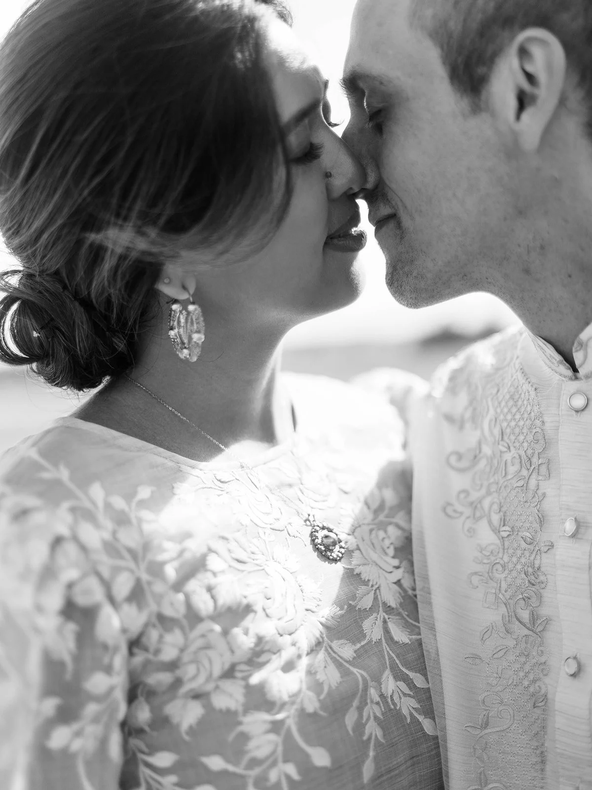 Black and white close-up of the bride and groom sharing an intimate moment, wearing traditional Filipino wedding attire outdoors at Pearson Field.