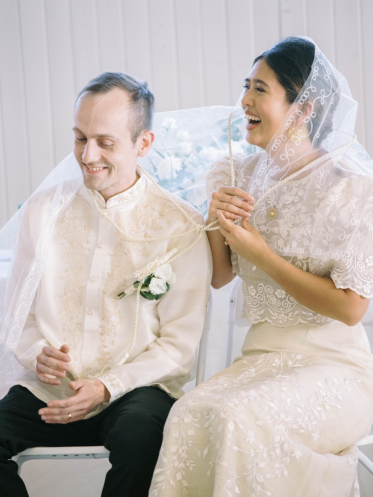 Bride tying a ceremonial cord around the groom during a traditional Filipino wedding ritual inside the Pearson Air Museum hangar.