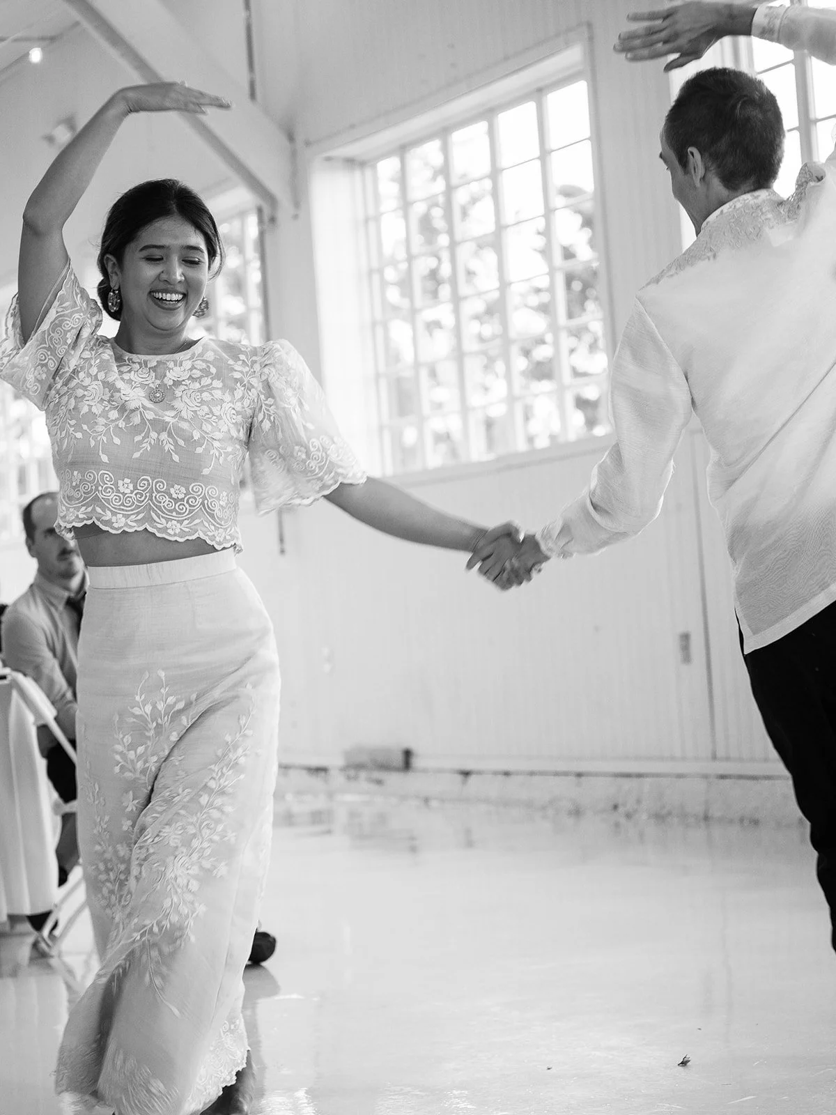 Bride and groom dancing barefoot together during a Filipino folk dance inside the Pearson Air Museum hangar.