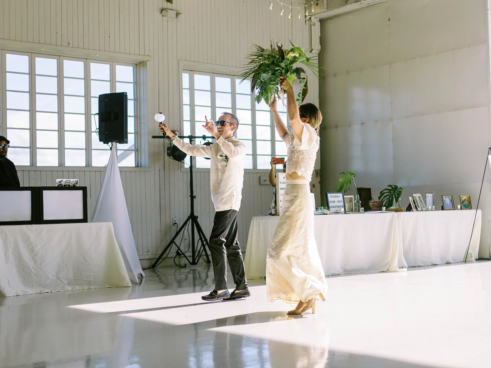 Bride and groom entering the Pearson Air Museum hangar reception, celebrating together while holding a tropical bouquet.