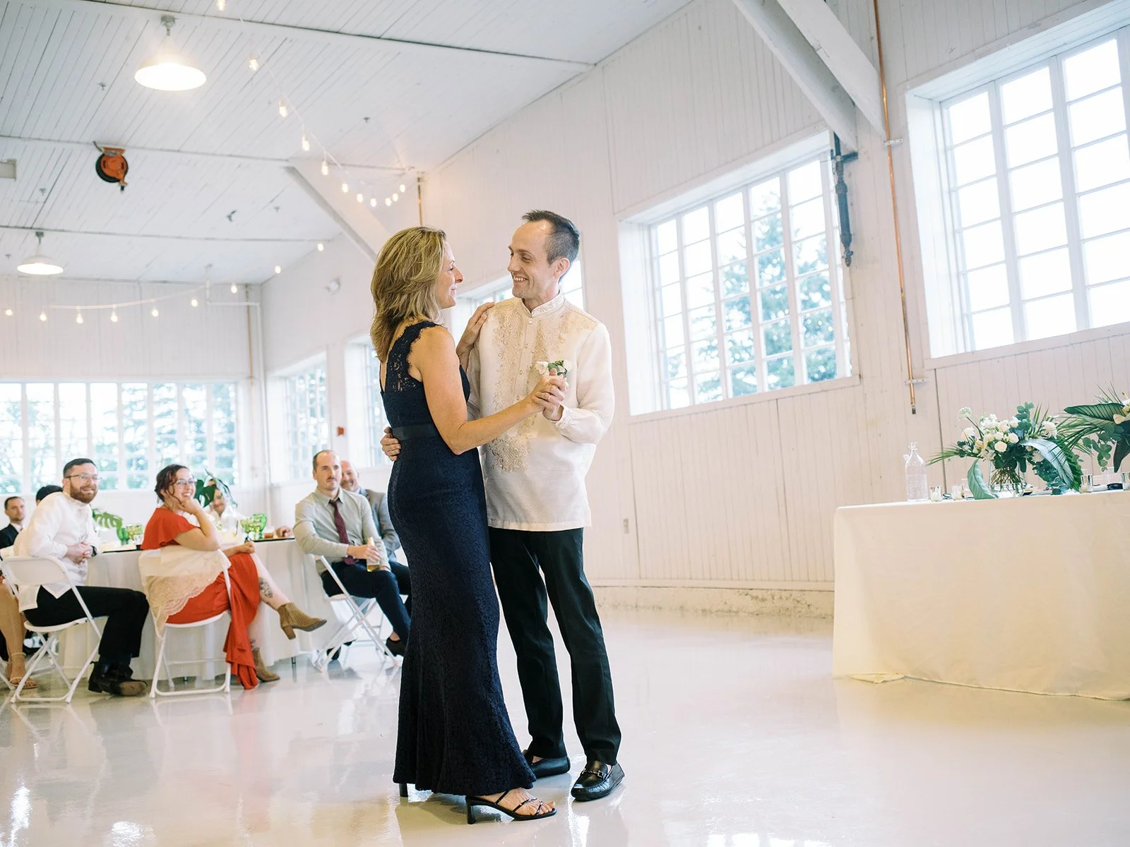 Groom dancing with his mother during the wedding reception inside the Pearson Air Museum hangar as guests look on.