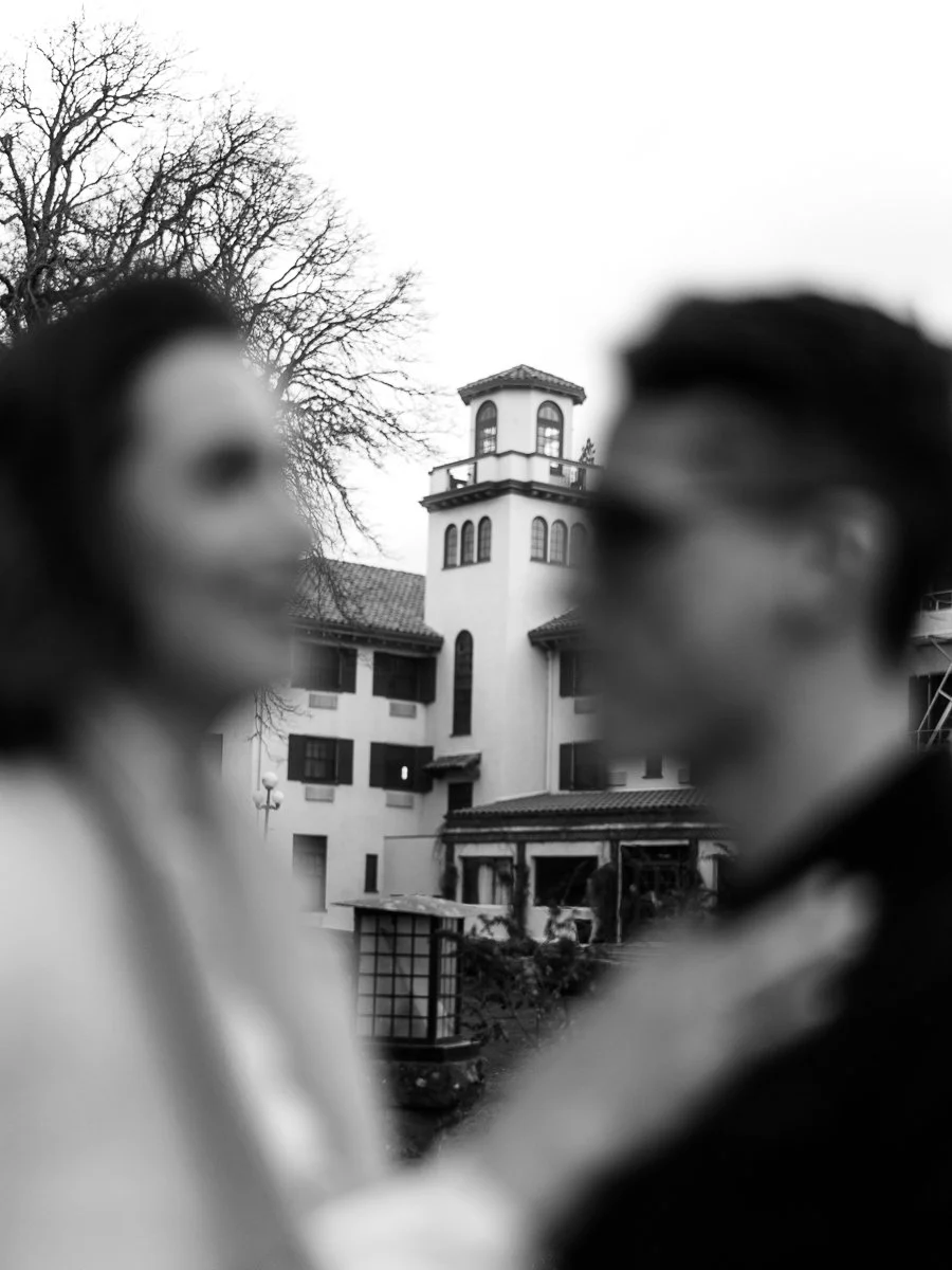 Soft-focus film photograph of the Columbia Gorge Hotel tower framed between two figures in the foreground.