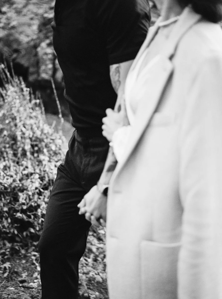Black and white film detail of the couple holding hands while walking, focused on movement and texture.