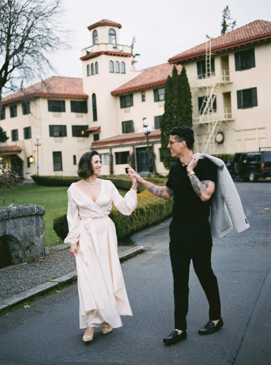 Couple walking together in front of the Columbia Gorge Hotel’s historic facade, photographed on color film.