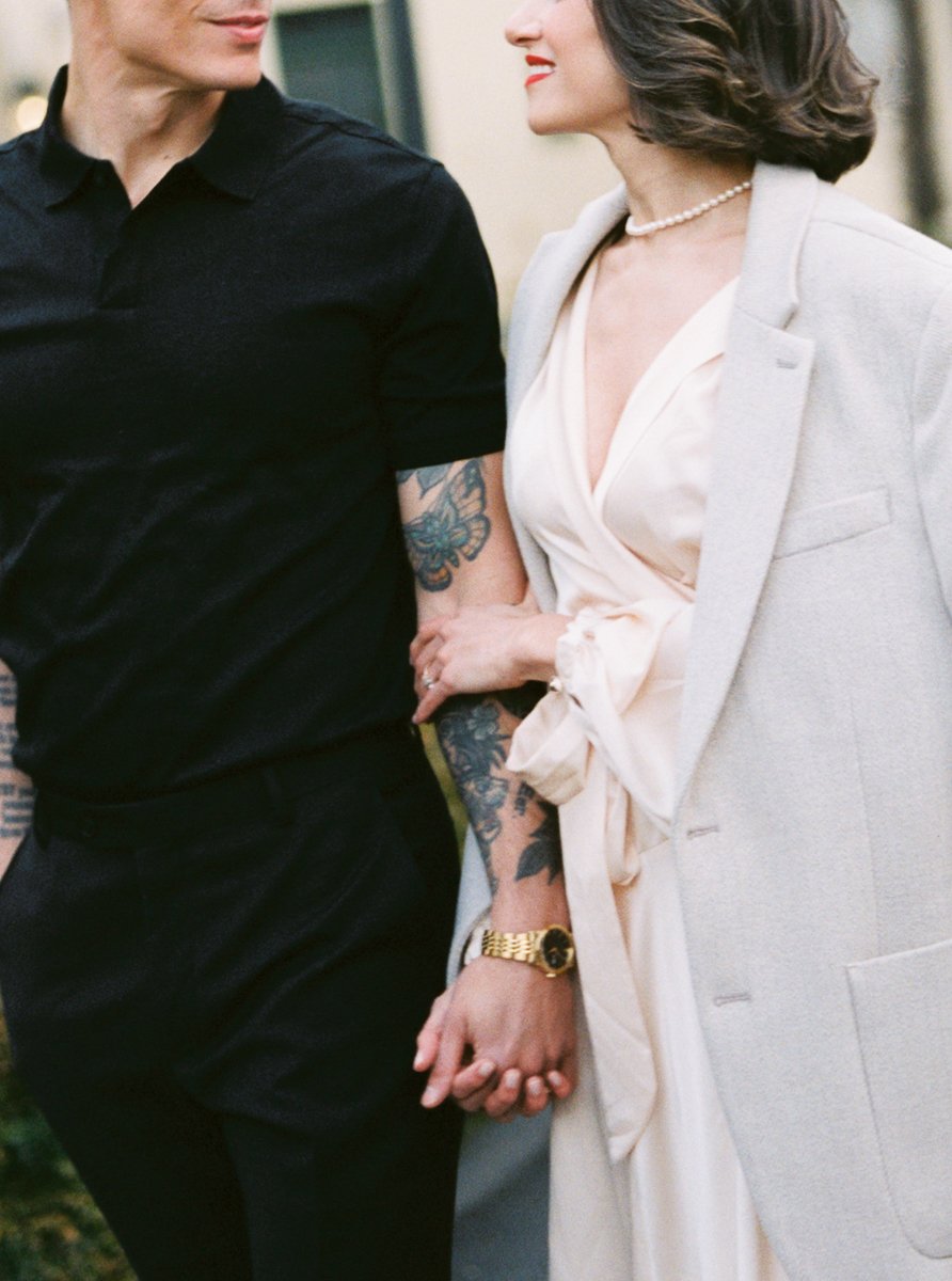 Close view of a couple walking arm in arm, hands intertwined, photographed on color film with soft focus and natural light.