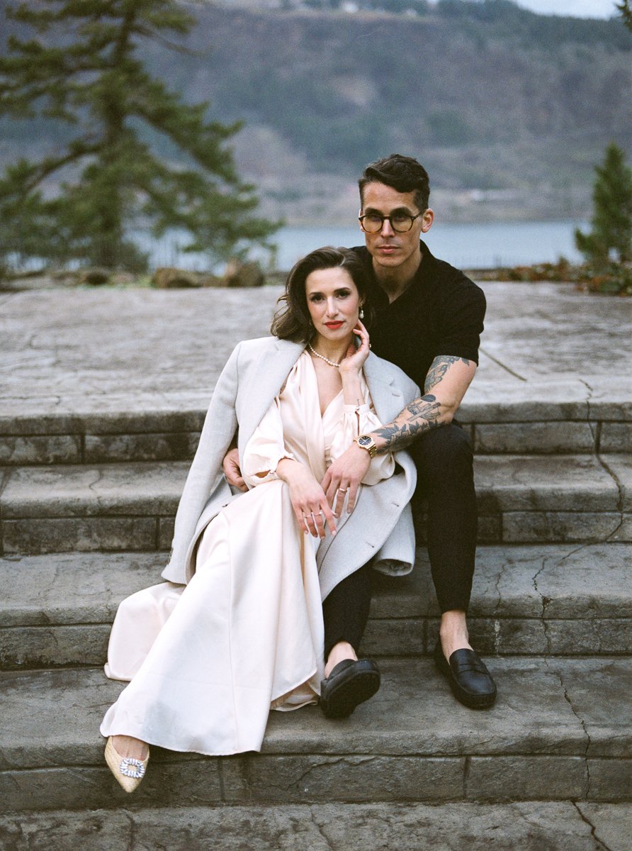Couple seated together on wide stone steps overlooking the Columbia River Gorge, photographed on color film with soft natural light.