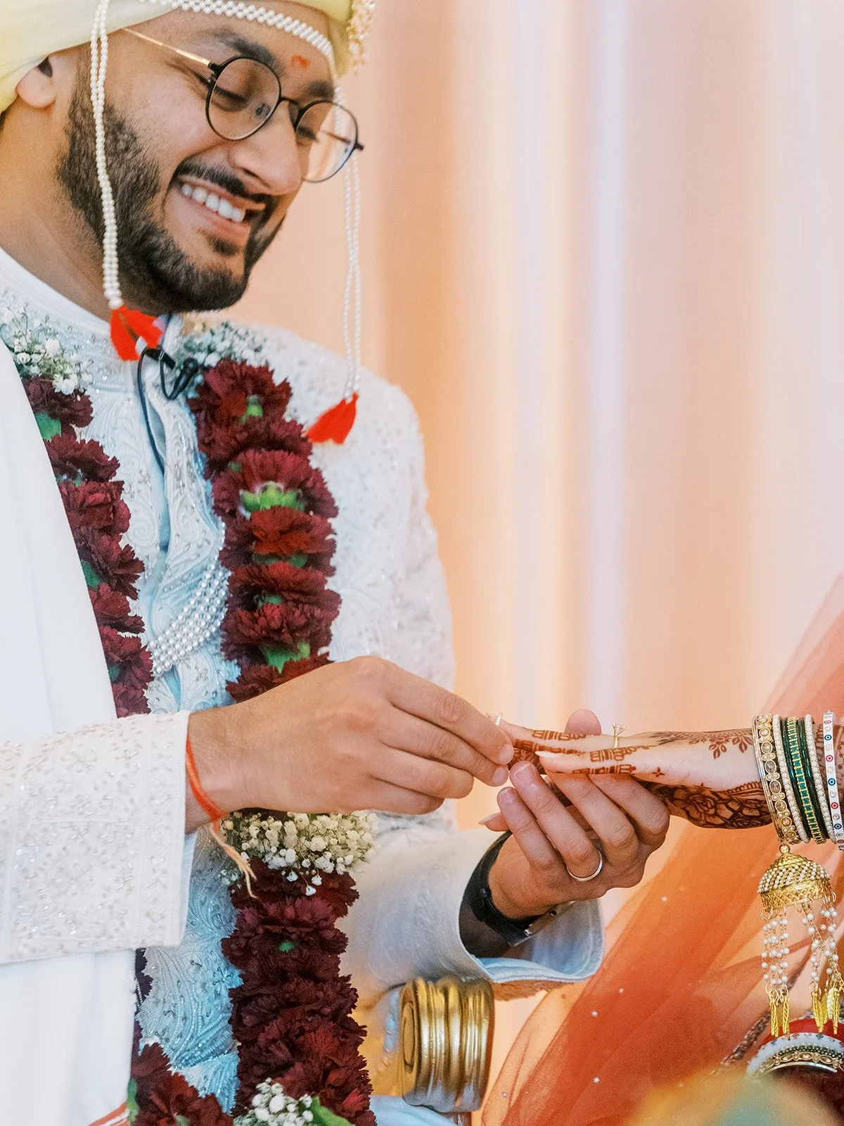 Groom placing diamond ring on bride’s hand during intimate Hindu wedding moment.