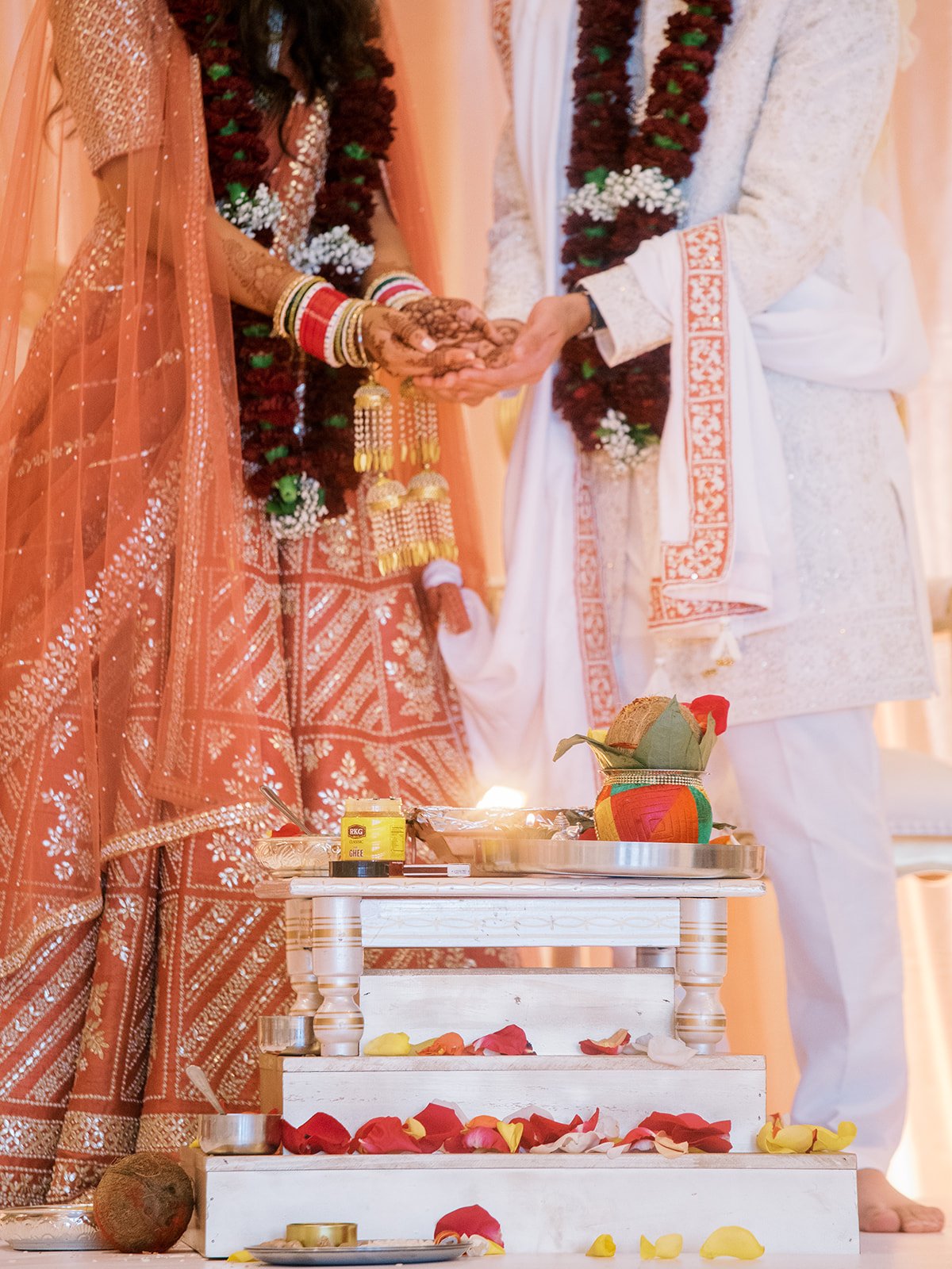 Bride and groom holding hands over sacred fire during Hindu wedding ritual