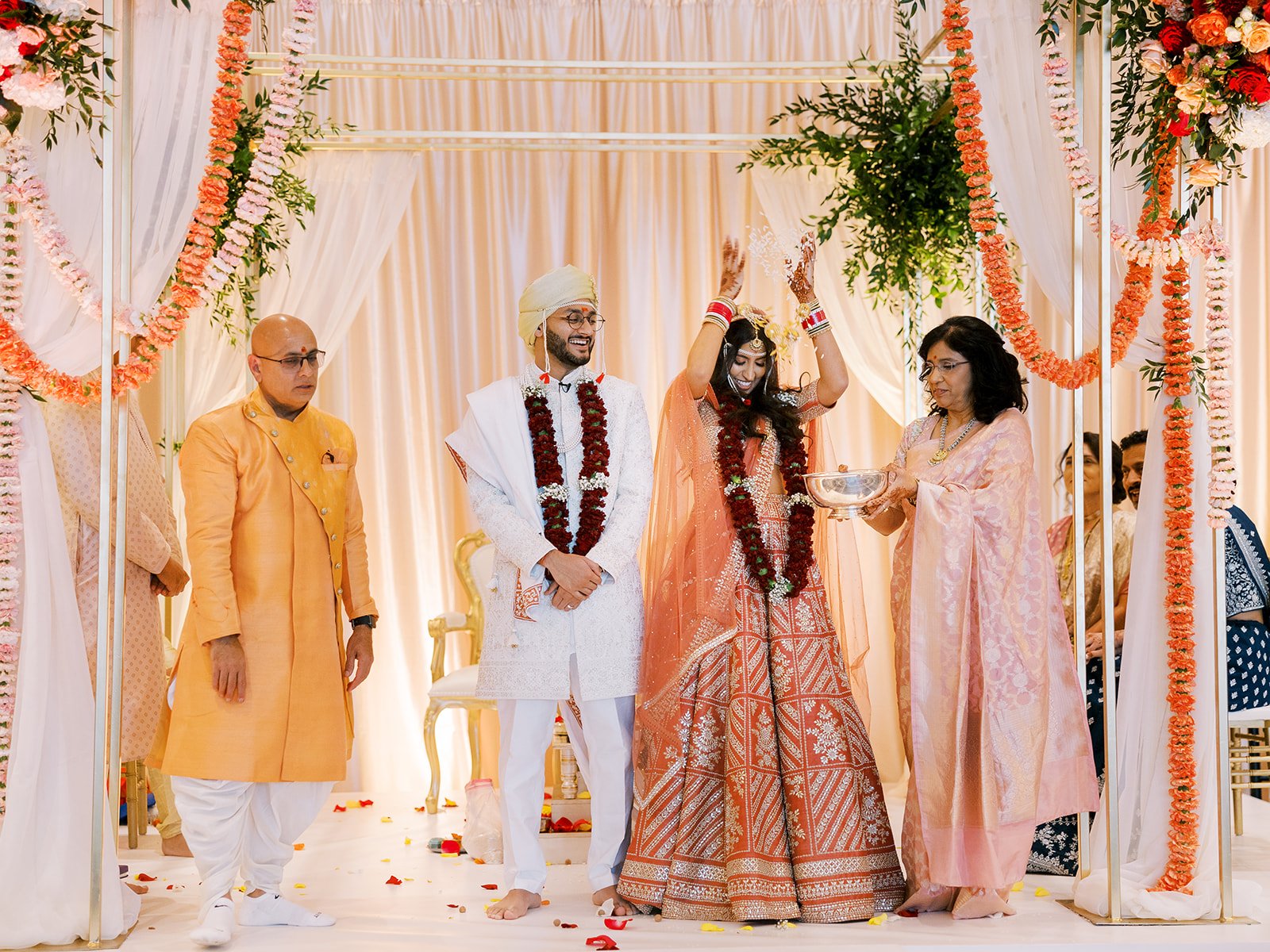 Bride raises hands as family performs traditional rice blessing ritual during Hindu wedding ceremony