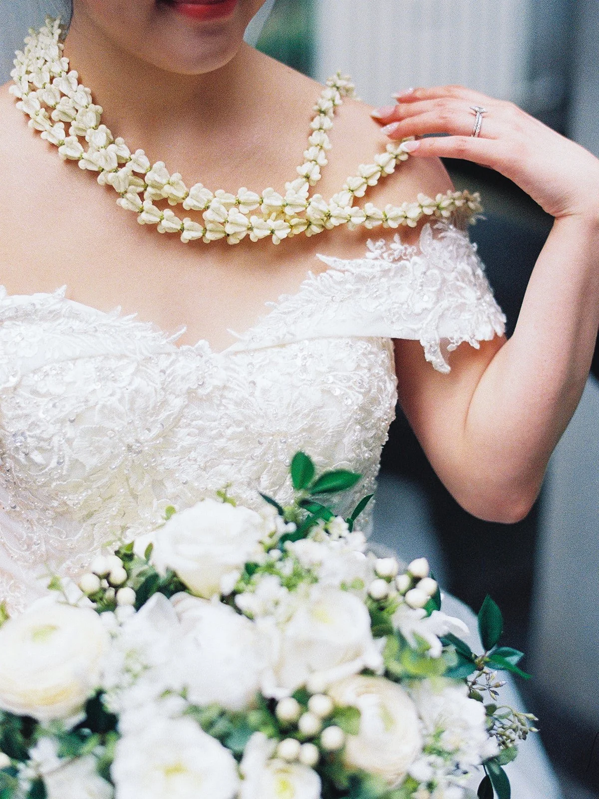 Close-up of bride wearing a traditional Vietnamese jasmine flower necklace with her wedding dress.