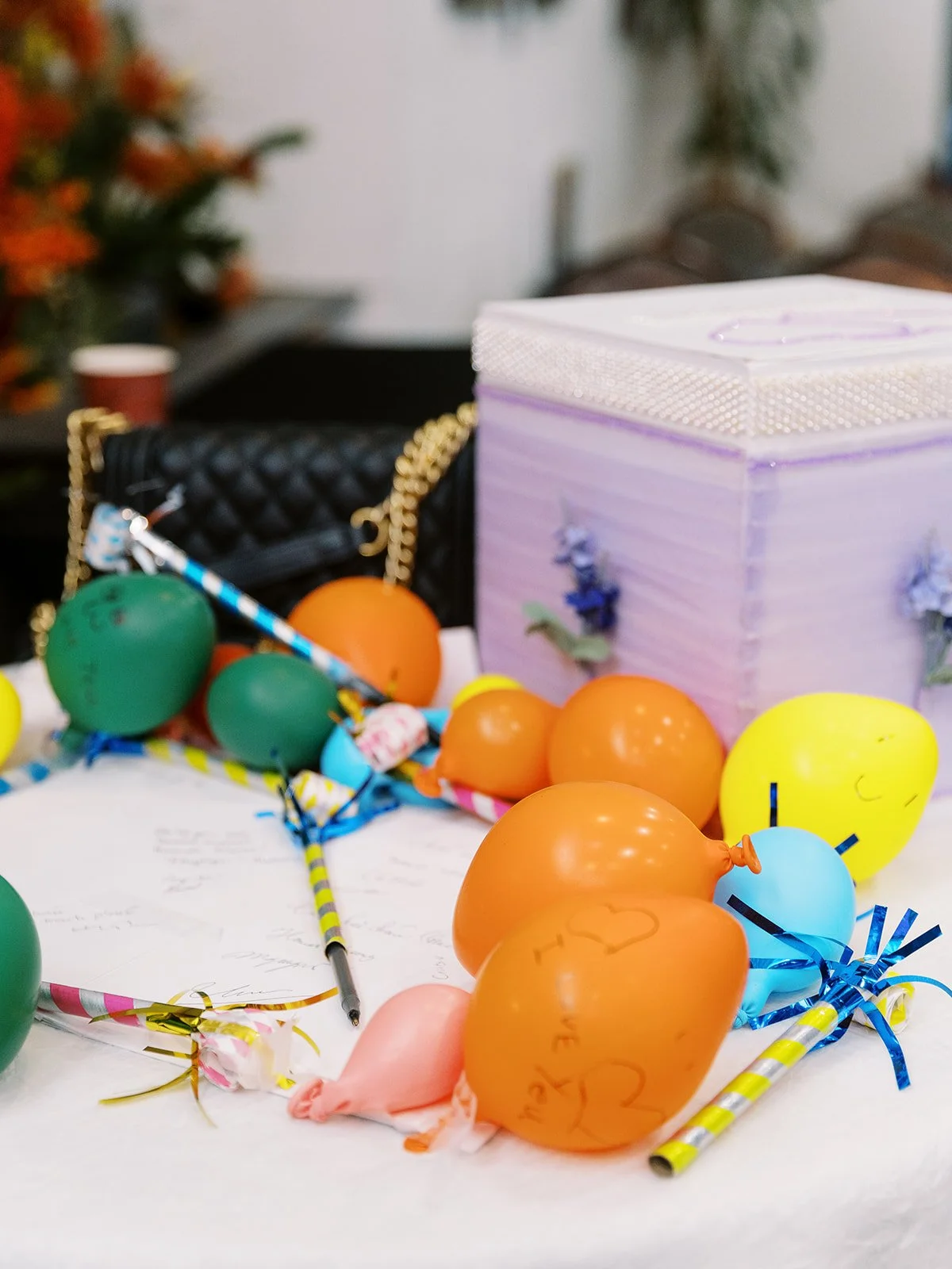 Reception guest book table with colorful balloons, pens, and a decorative gift box.
