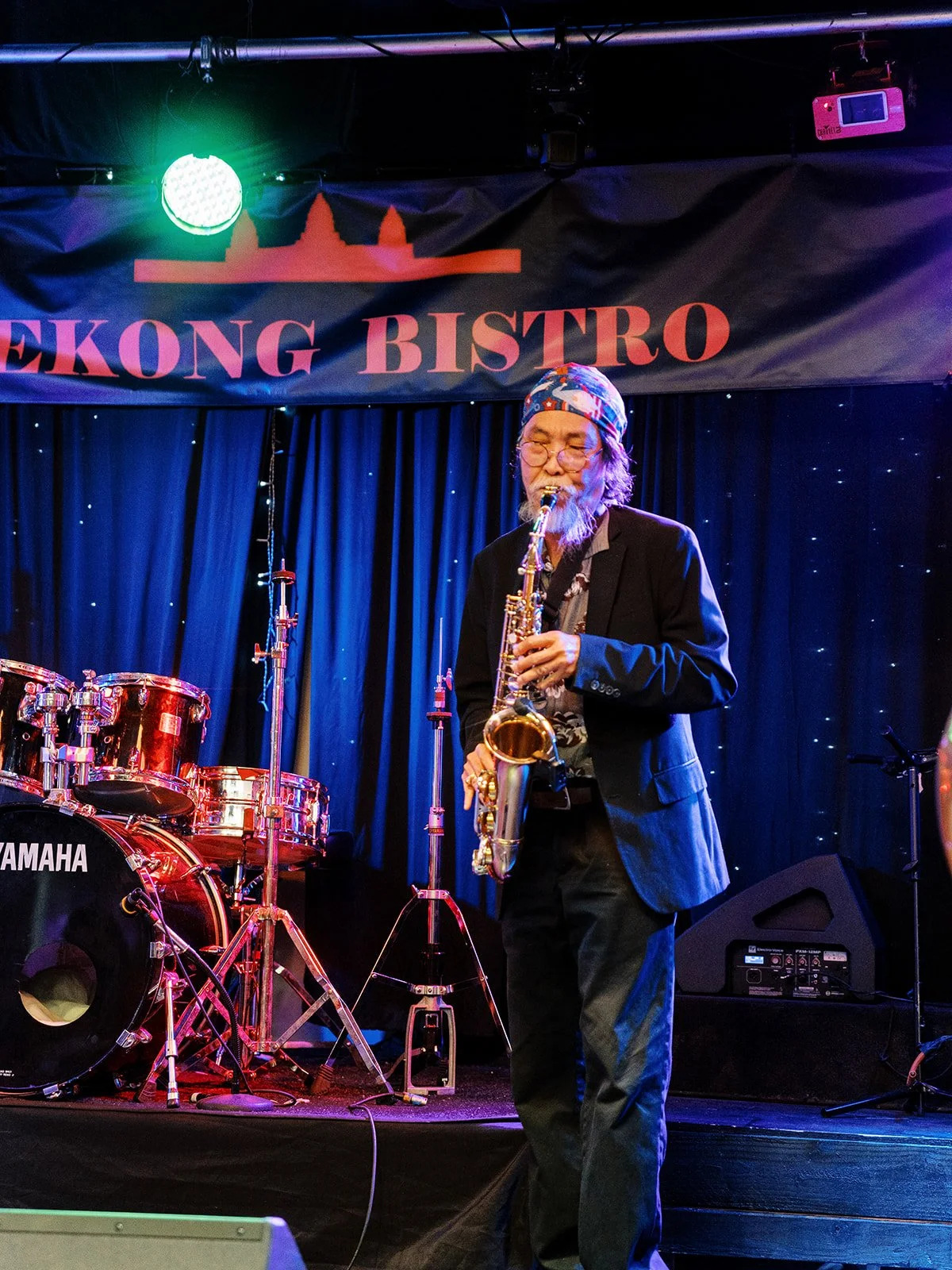 Saxophone player performing on stage under colorful lights during the wedding reception.