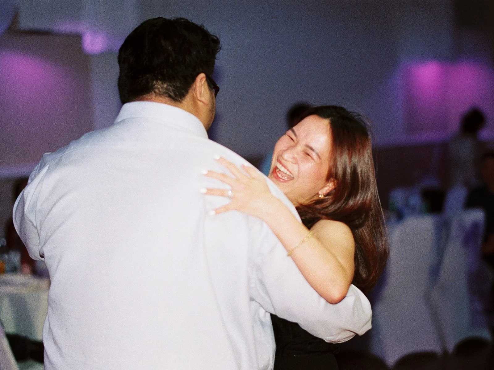 Wedding guests dancing together on the reception dance floor under colorful lighting.