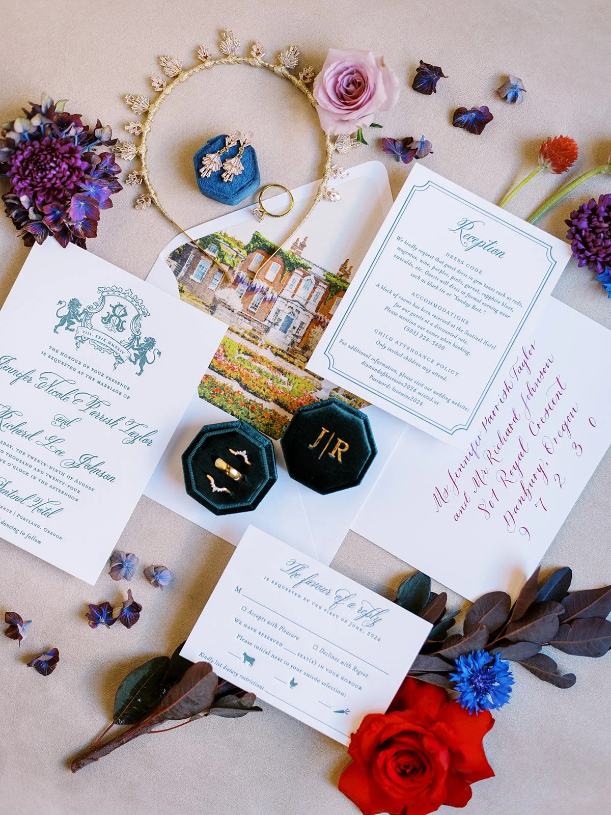 Wedding invitation suite with envelope liner, rings, earrings, and colorful flowers arranged in styled flat lay.