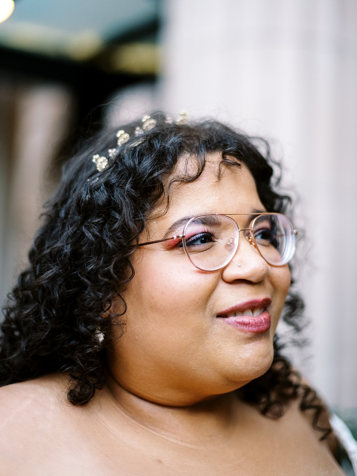 Close-up portrait of bride wearing glasses and delicate hairpiece.