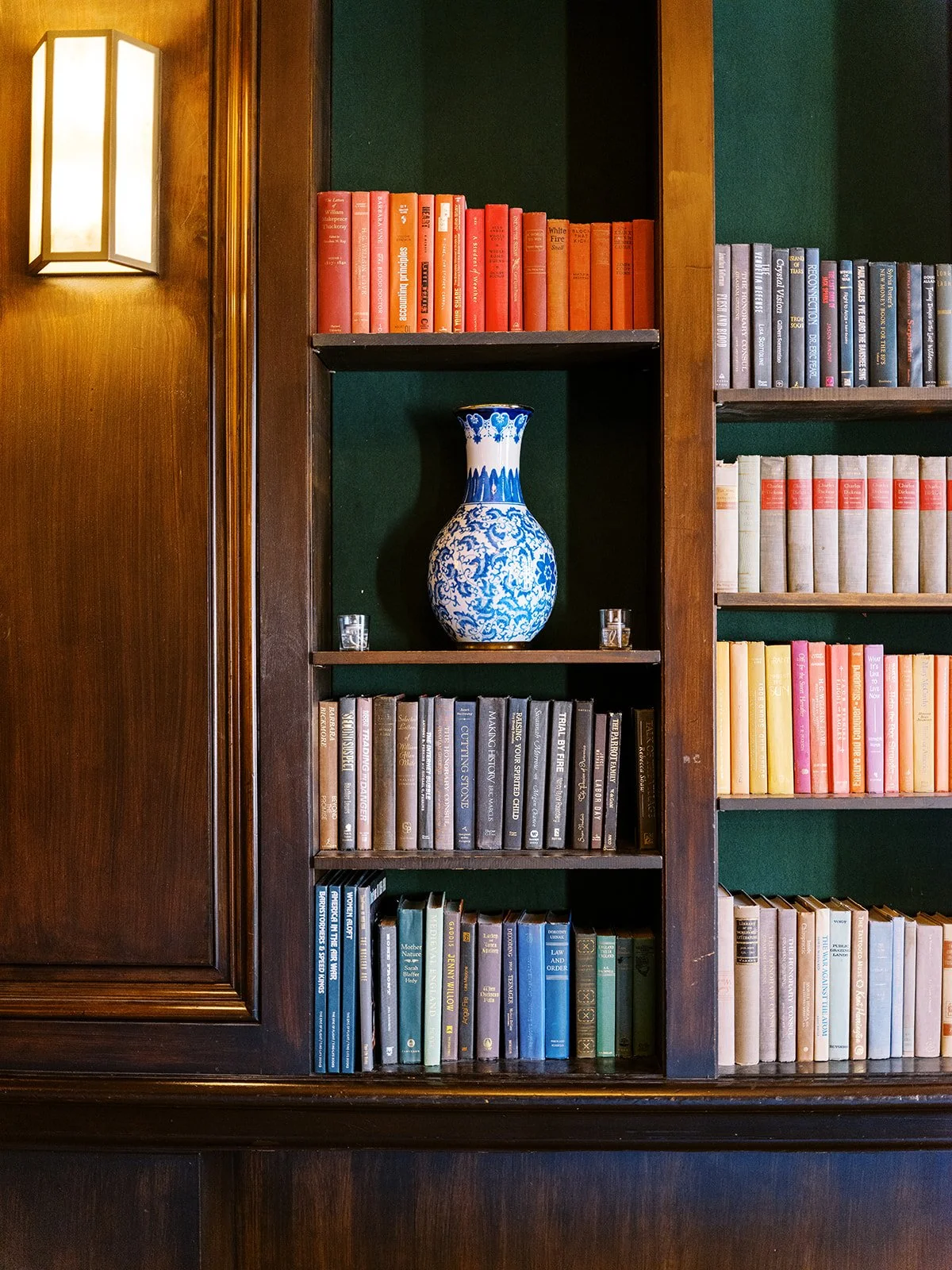 Wood bookshelves with colorful books and blue ceramic vase in historic hotel library.