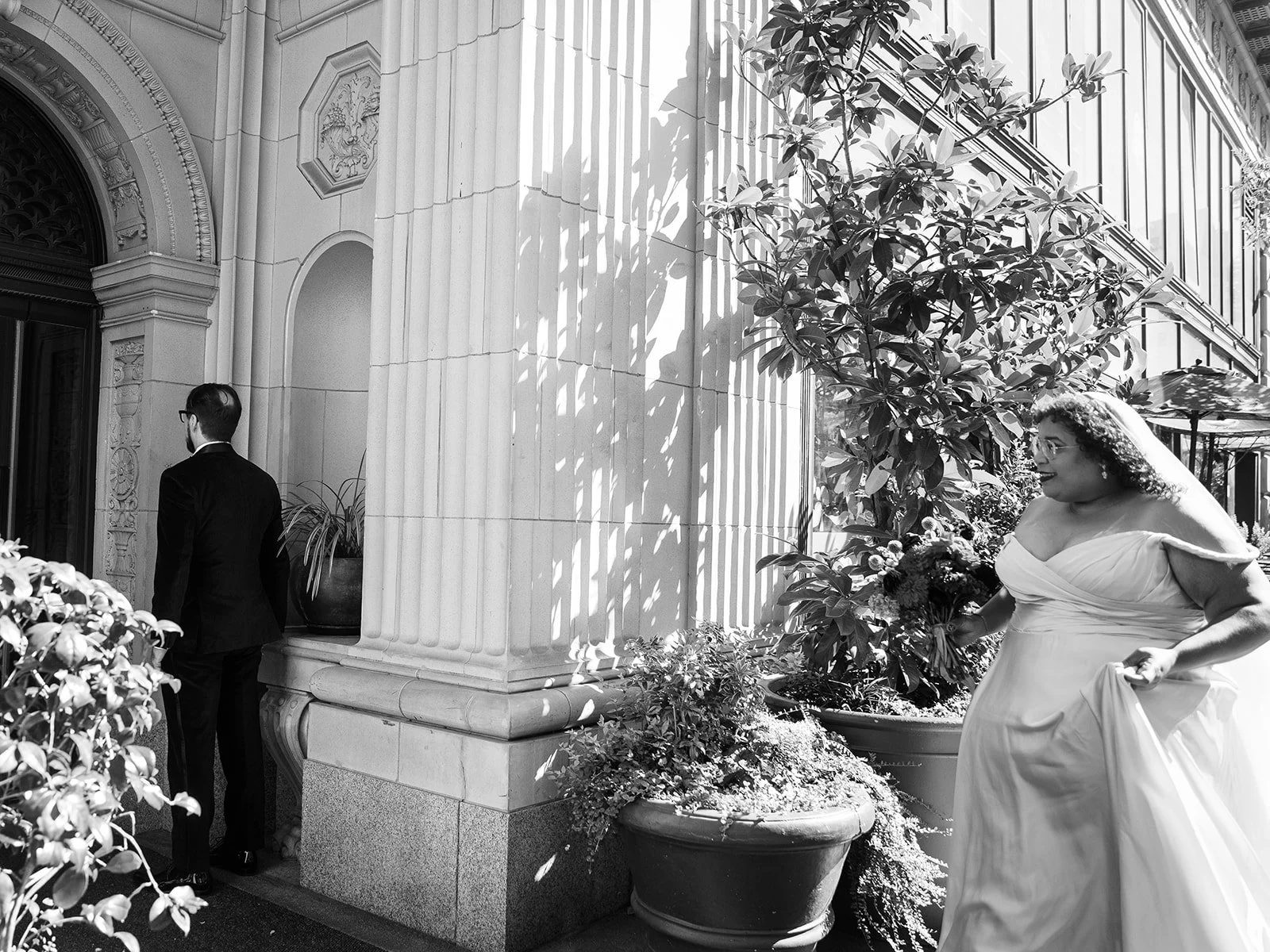 Bride approaching groom for first look outside historic building with large stone columns.