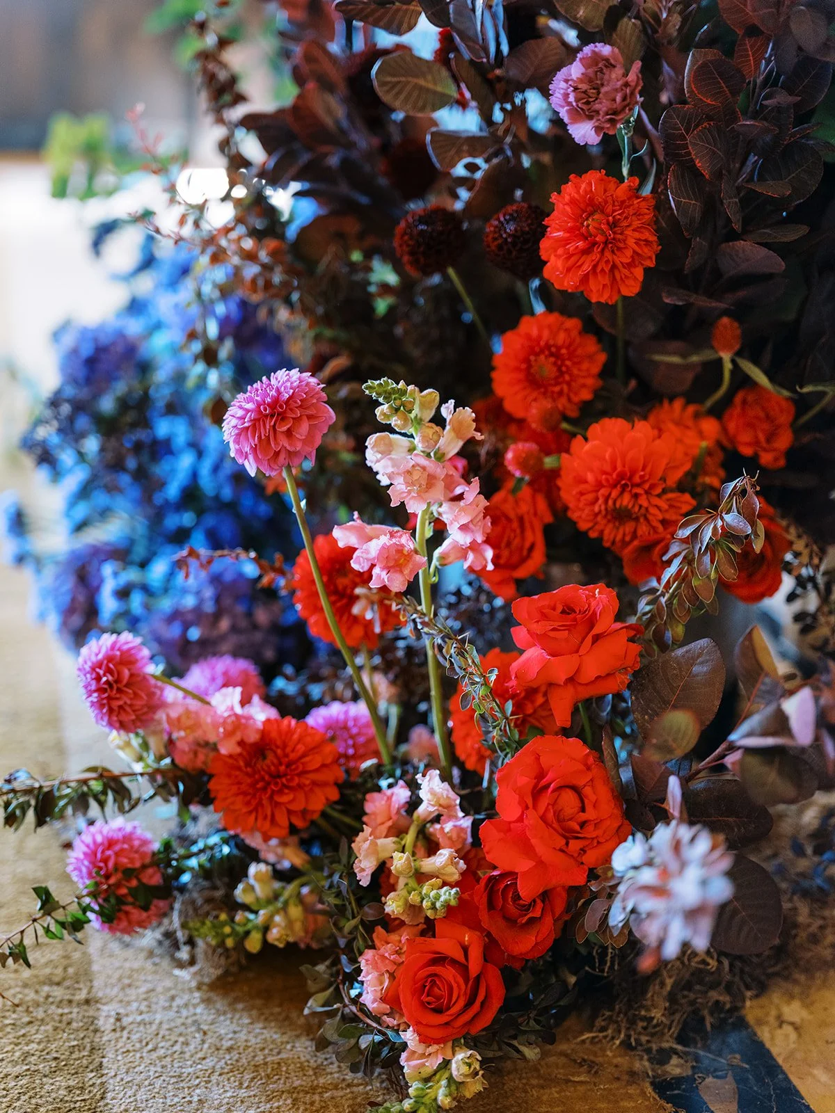 Colorful ceremony floral arrangement with red roses, dahlias, and pink flowers.