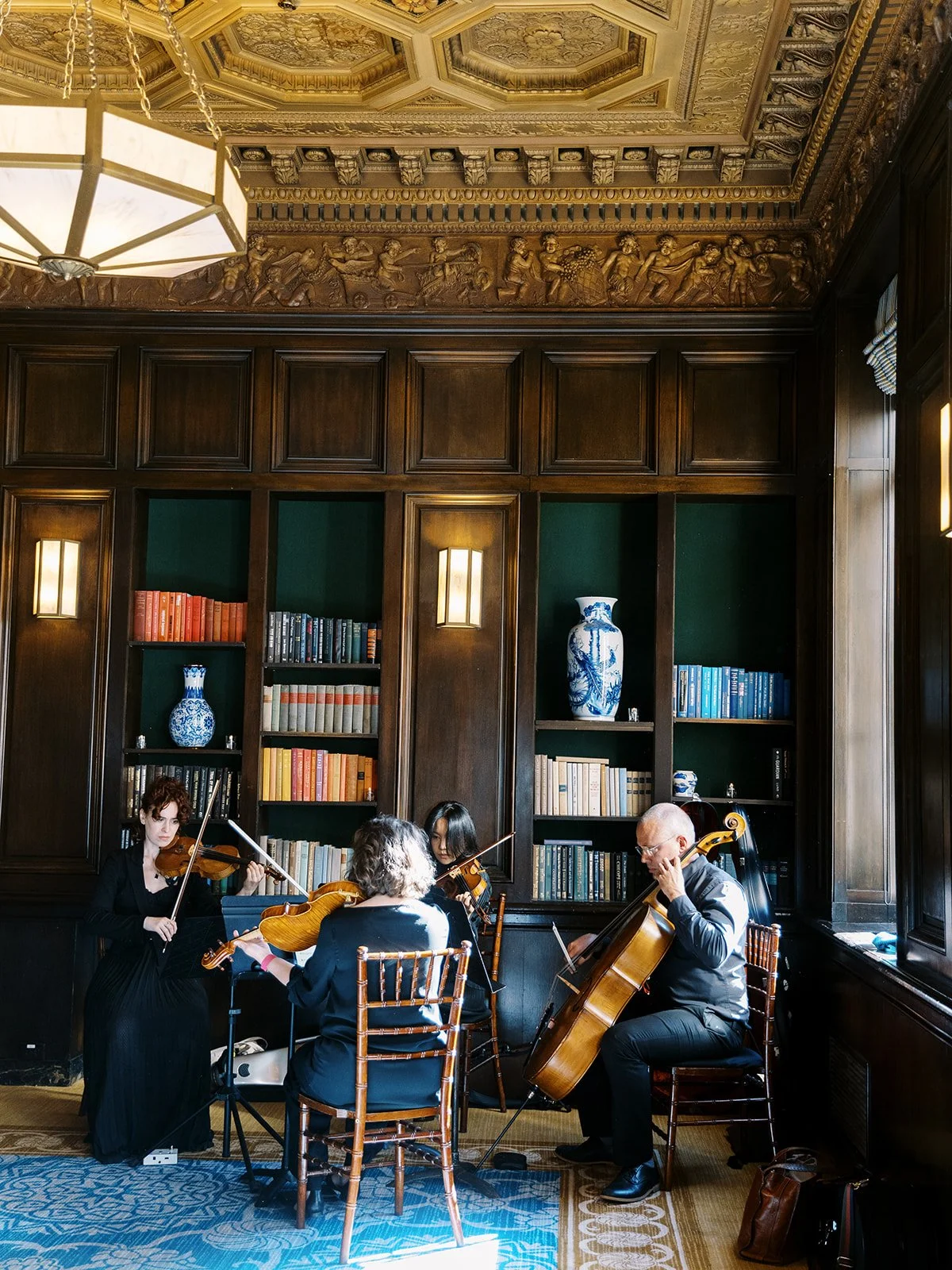 String quartet performing during ceremony in wood-paneled hotel library.
