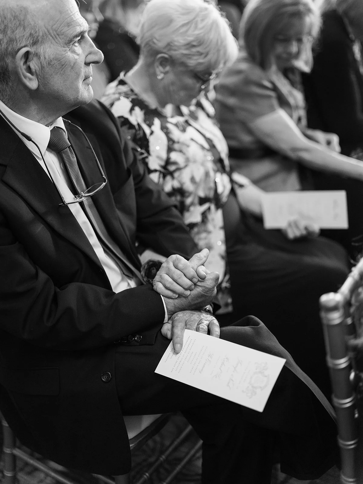 Wedding guest holding ceremony program while seated during ceremony.