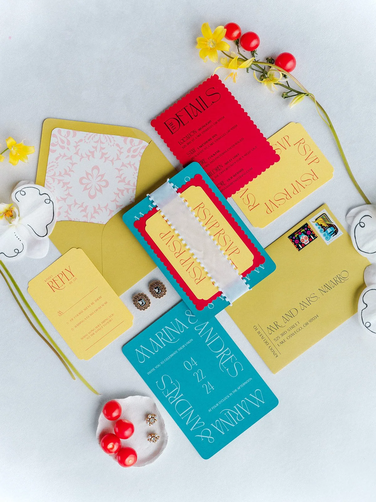 Colorful wedding invitation suite with red, yellow, and teal cards, envelopes, and floral accents for Portland Oregon wedding