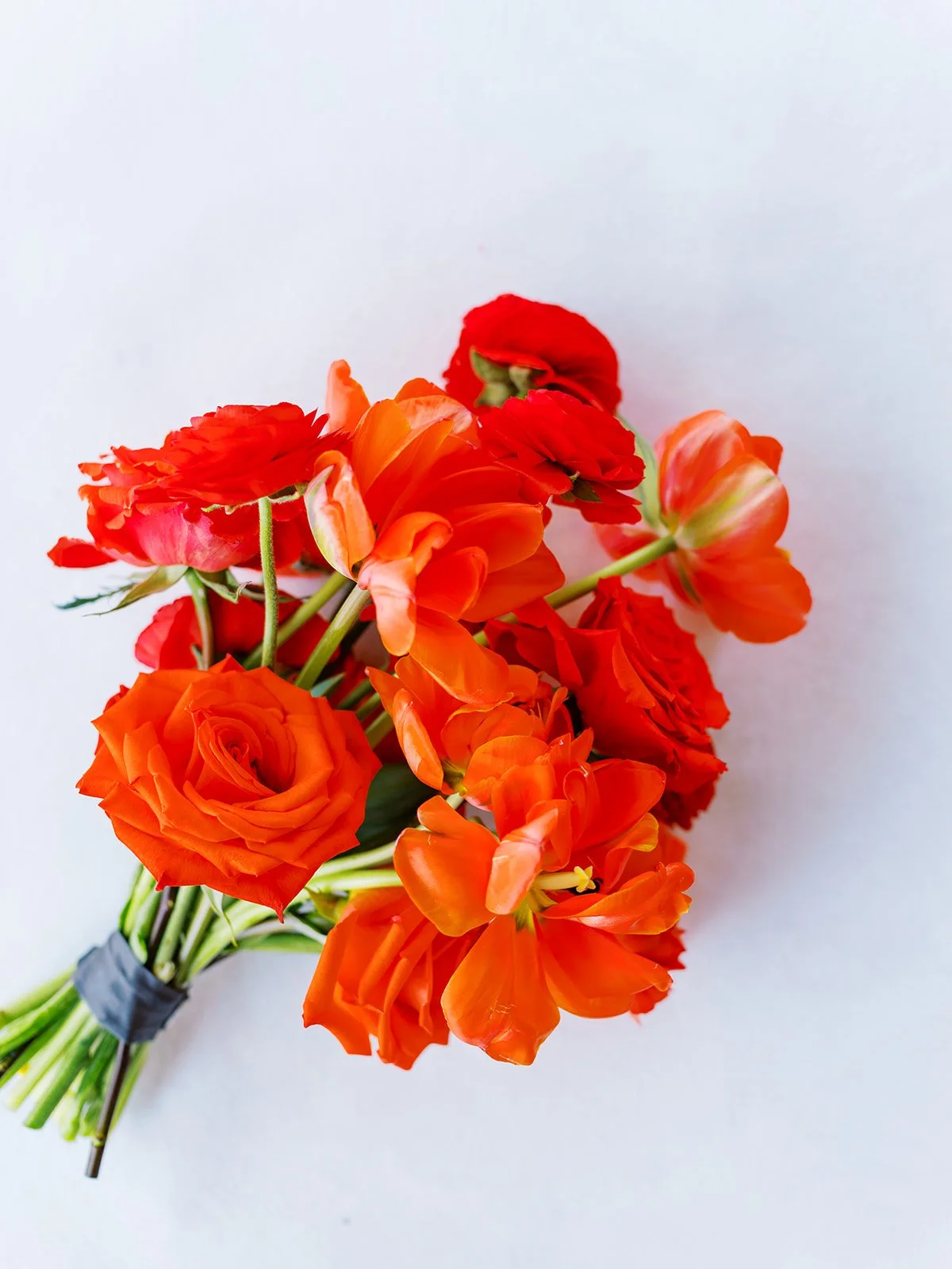 Bright orange wedding bouquet with roses and ranunculus on light background for Portland Oregon wedding