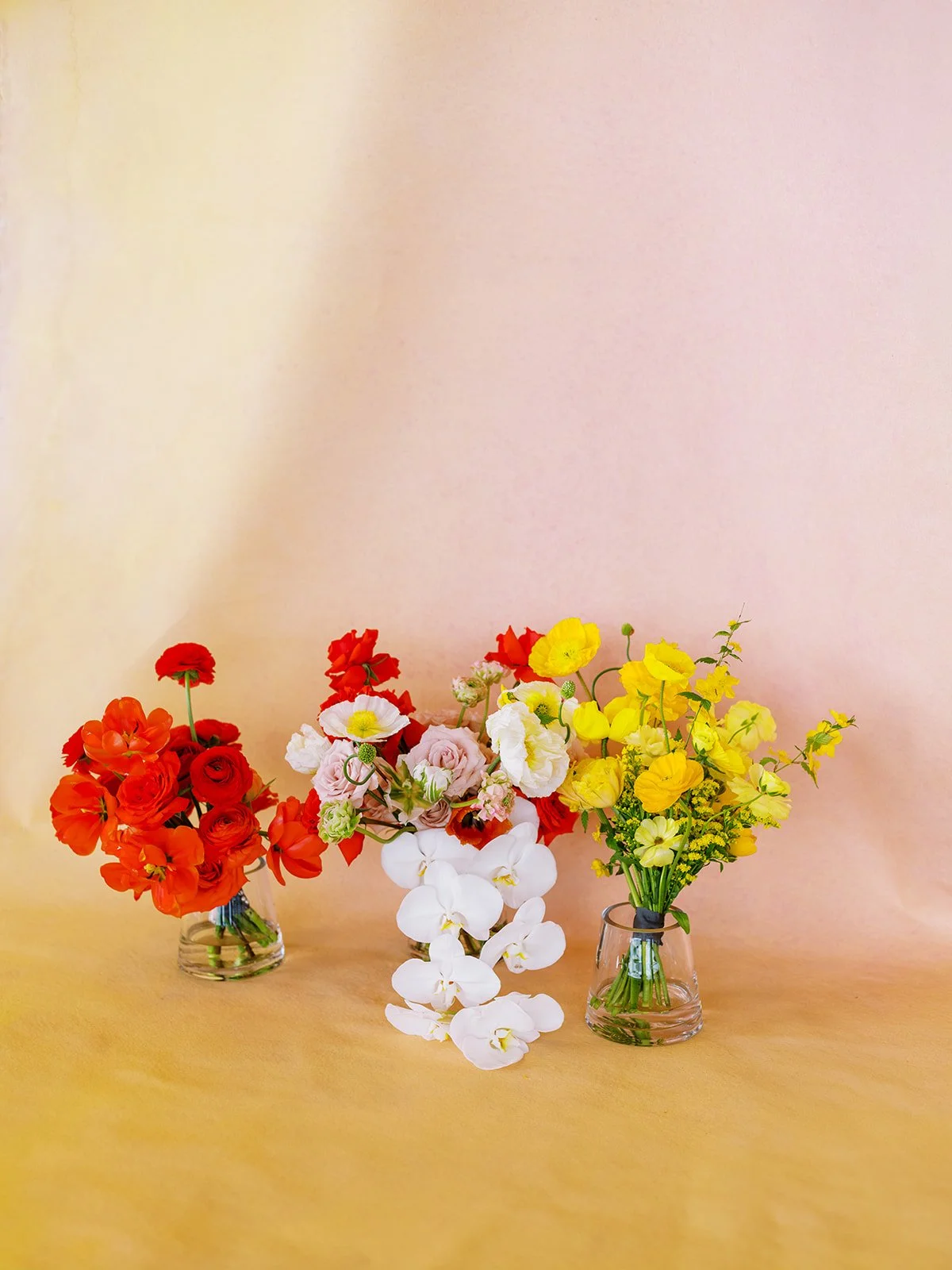 Colorful floral arrangements in red, white, and yellow displayed in glass vases for Portland Oregon wedding decor