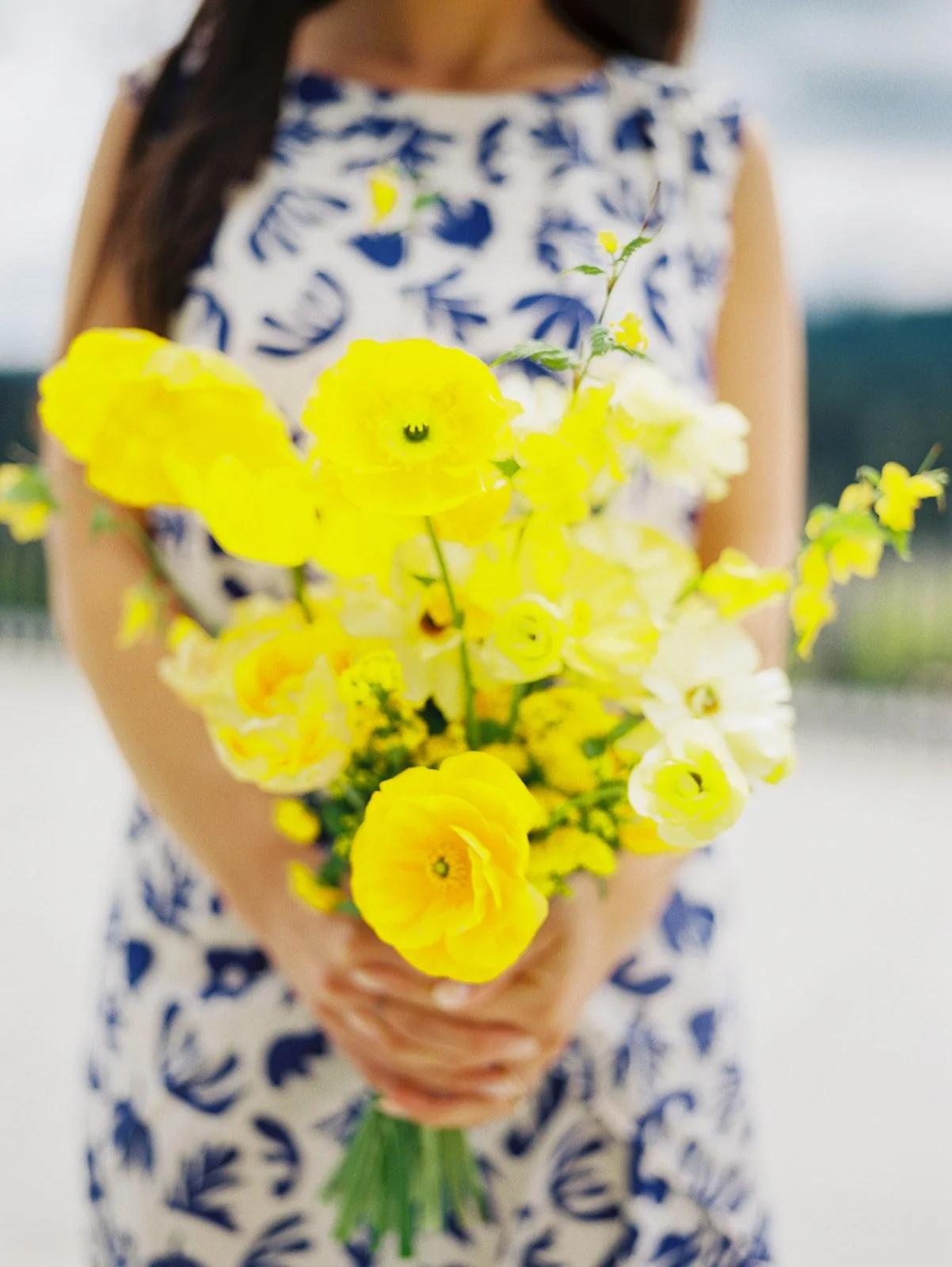 Bridesmaid holding yellow and white bouquet with ranunculus and wildflowers at Portland Oregon wedding