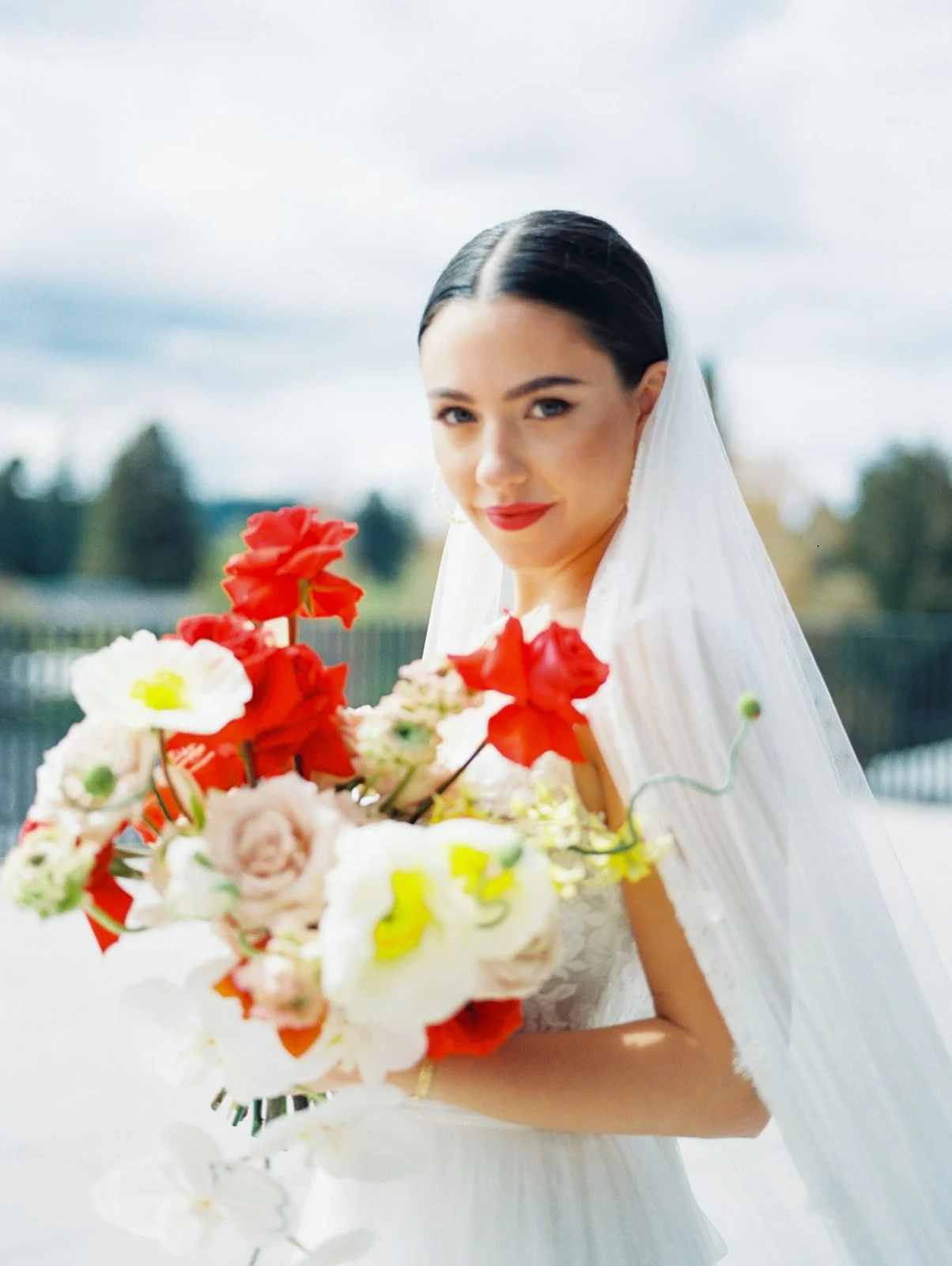 Bride in lace gown and veil holding colorful bouquet on rooftop at Ironlight wedding in Oregon