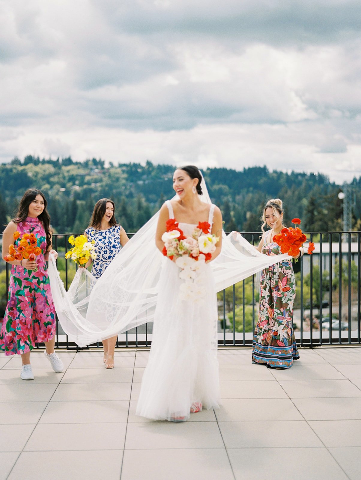 Bridal party walking with flowing veil and colorful bouquets at Ironlight rooftop wedding in Oregon