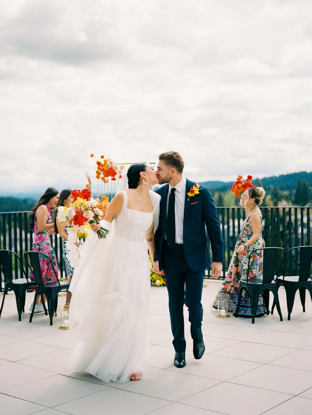 Bride and groom kissing while walking down aisle after ceremony with guests cheering