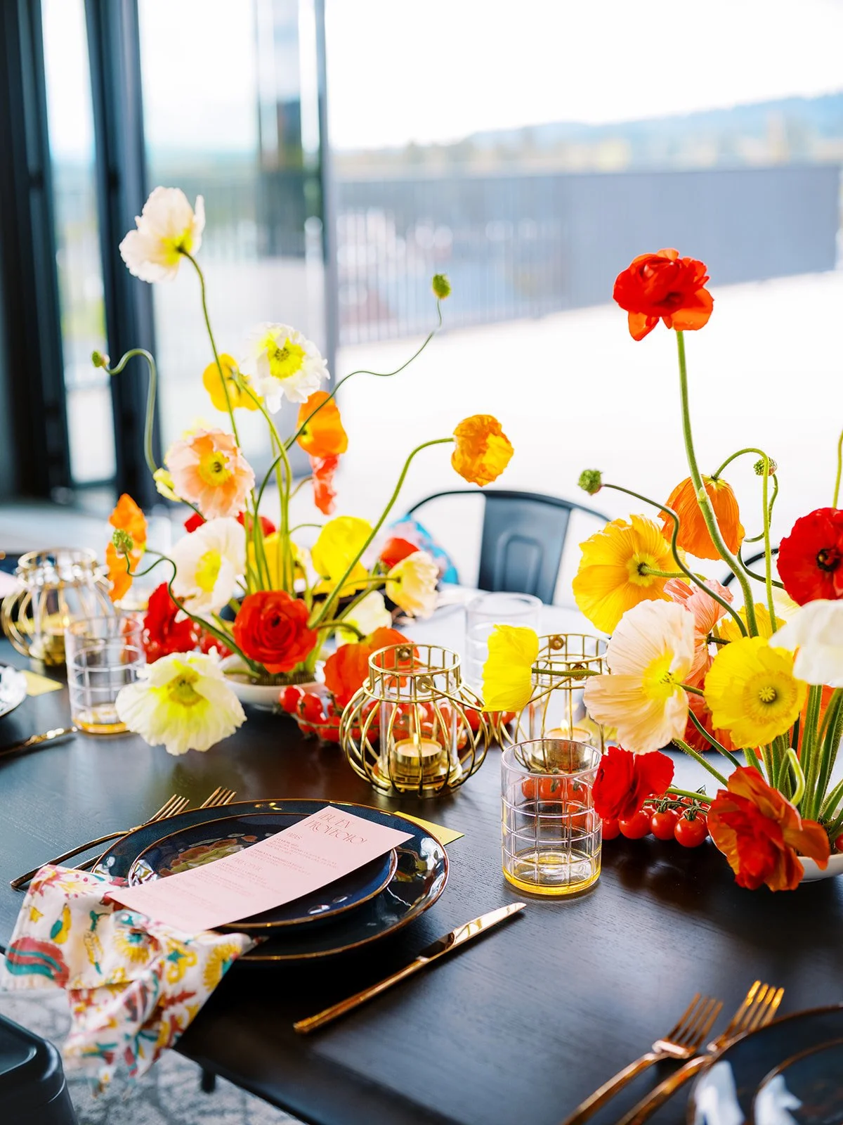 Reception table with bright floral centerpieces, gold accents, and modern place settings