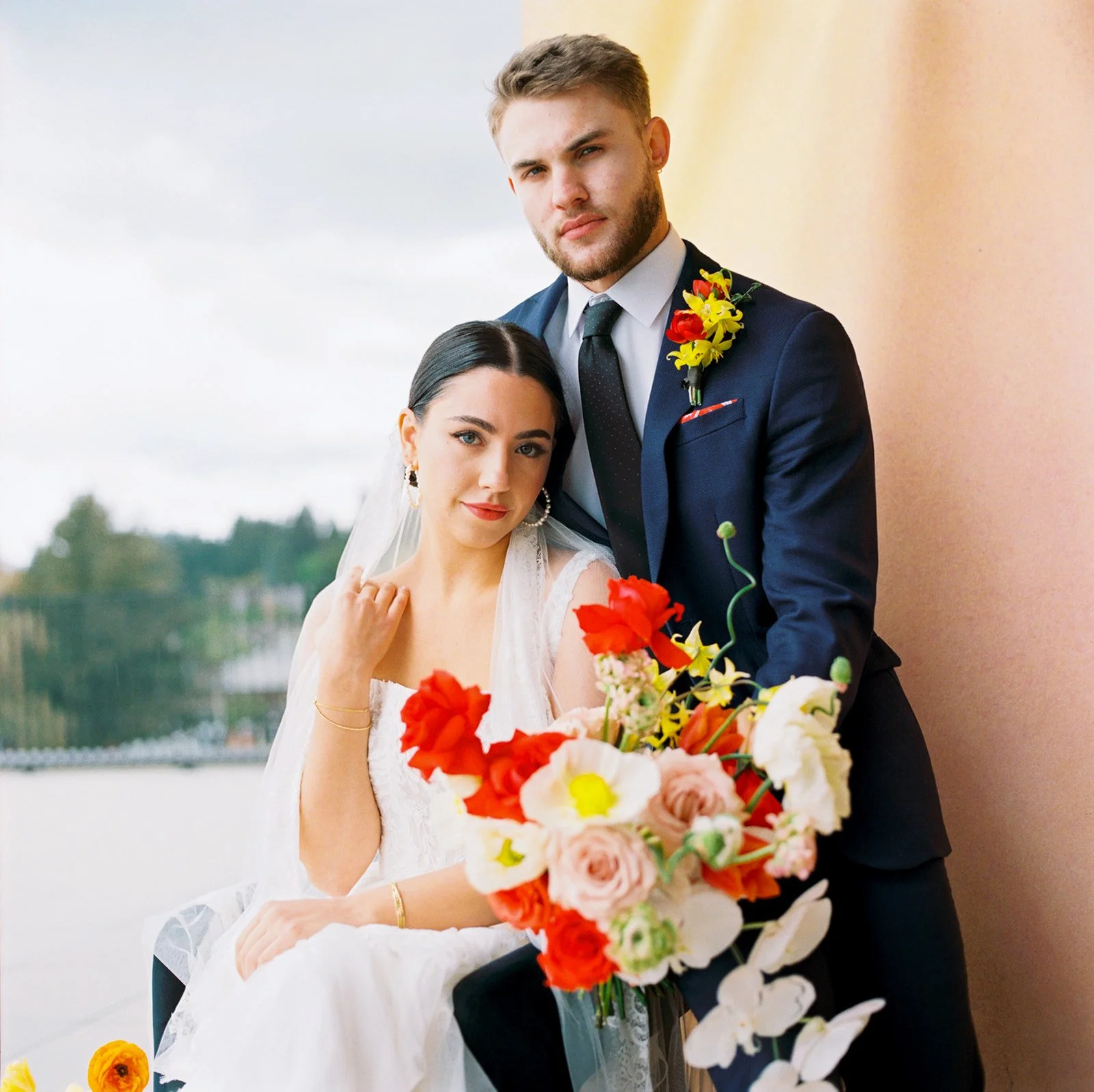 Bride and groom posing together with colorful bouquet in foreground on rooftop terrace