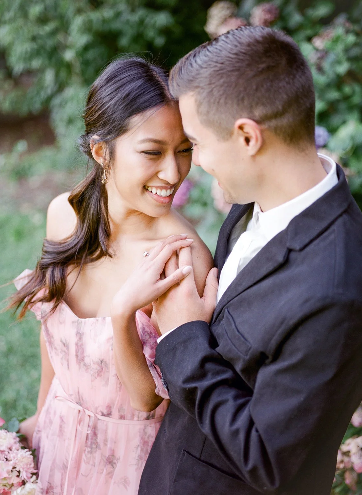Close-up of couple smiling and touching hands in soft natural light at Cathedral Park.