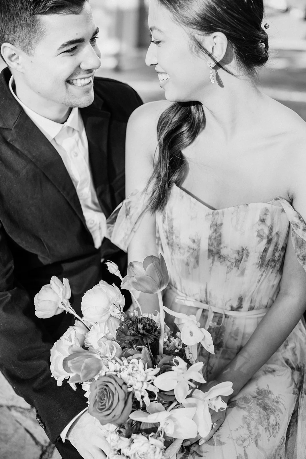 Black and white close-up of couple smiling together with bouquet at Cathedral Park.