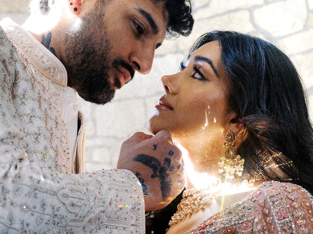 Romantic close-up of South Asian couple in ornate wedding attire with sunlight reflecting through crystal bridal jewelry.