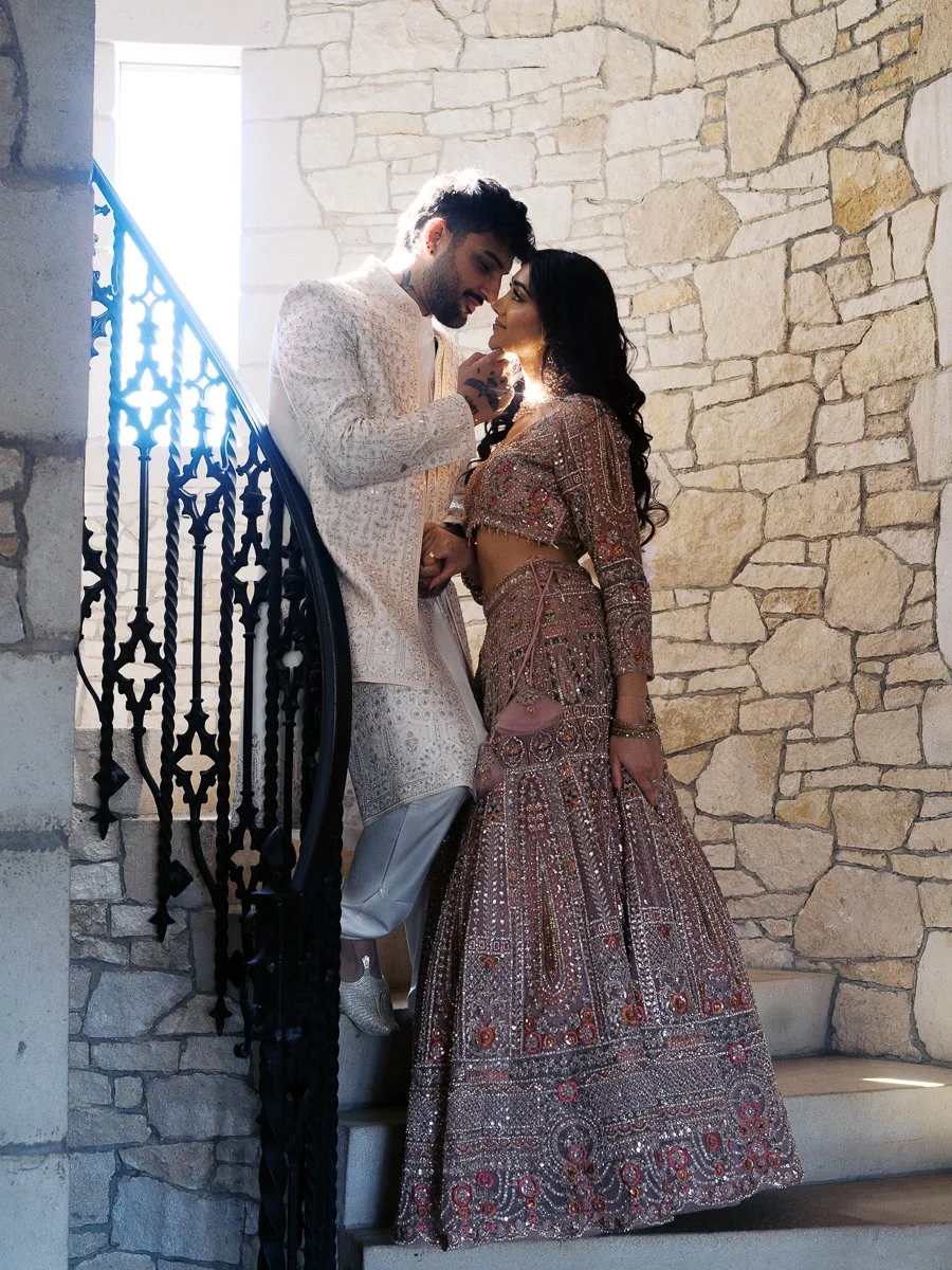 Wedding couple in traditional Indian attire posing together on a stone staircase at Chateau de Lis.