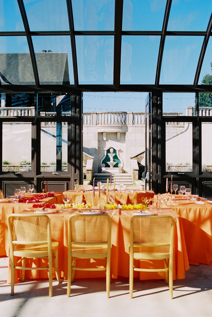 Reception tables with warm orange linens overlooking the formal courtyard at Chateau de Lis wedding venue.