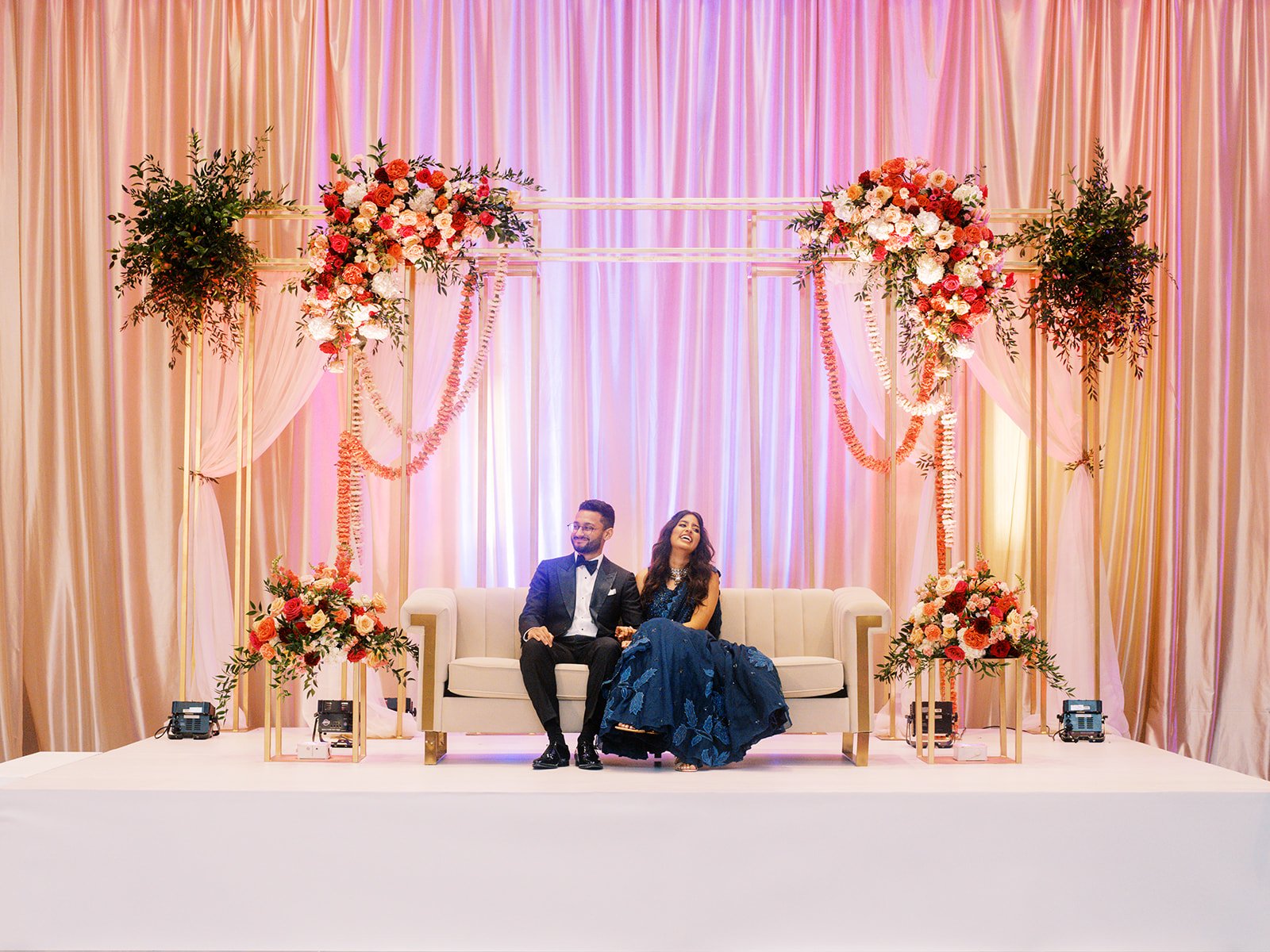 Couple seated beneath a colorful floral wedding backdrop during a Hyatt Regency Portland reception.