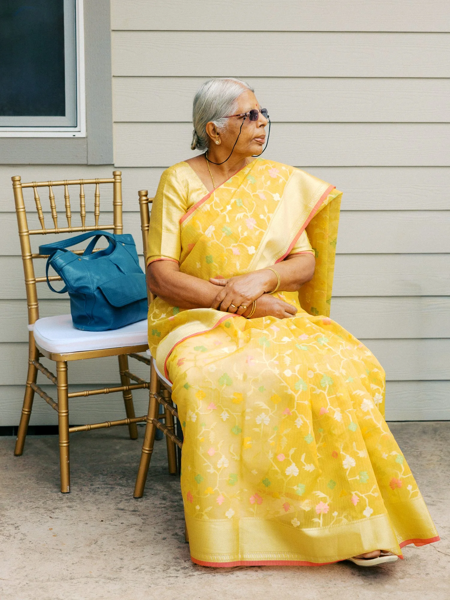 Older guest in a yellow floral sari seated outdoors during the Haldi ceremony.