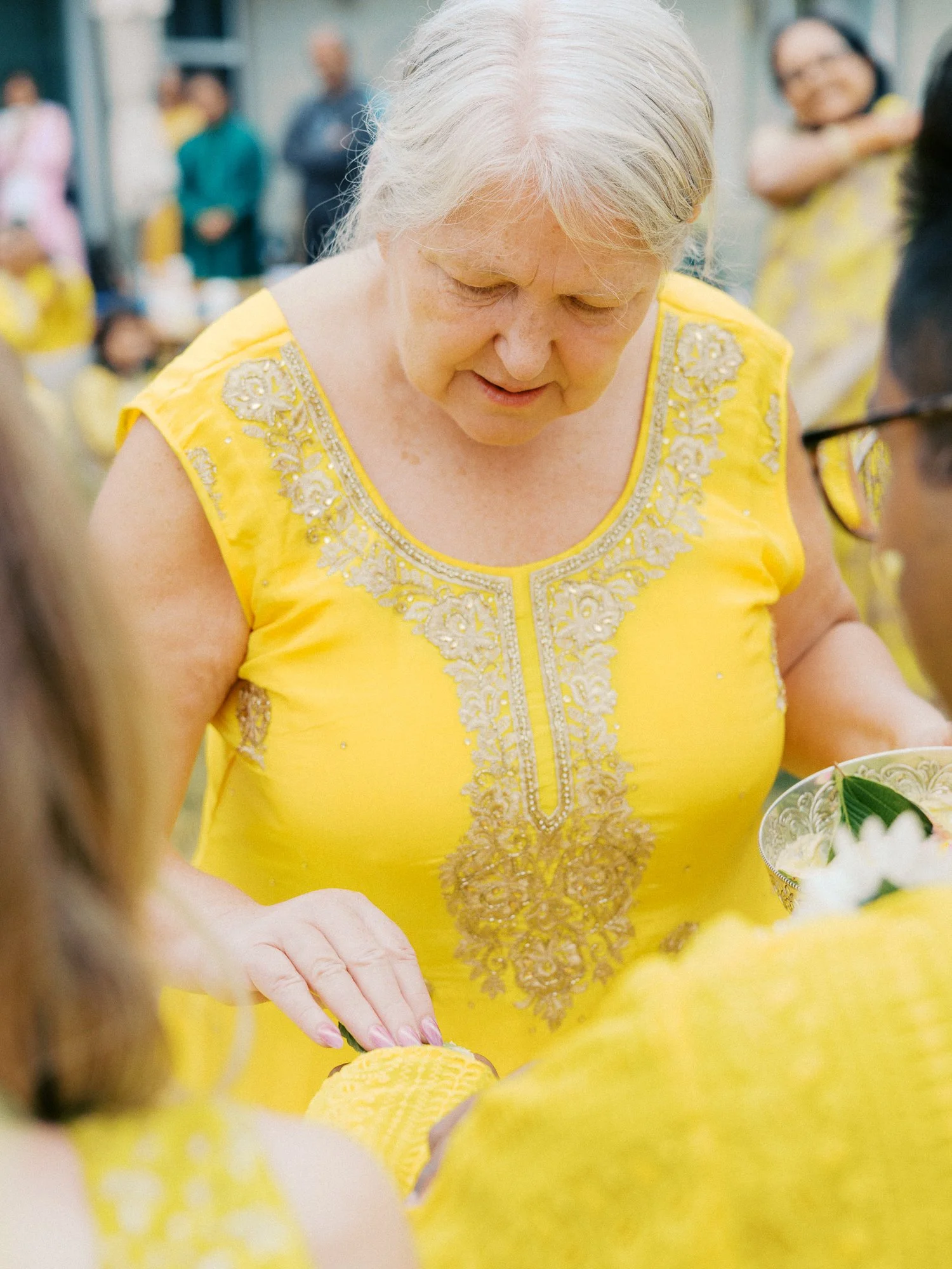 Guest in a yellow embroidered outfit taking part in the outdoor Haldi ritual.