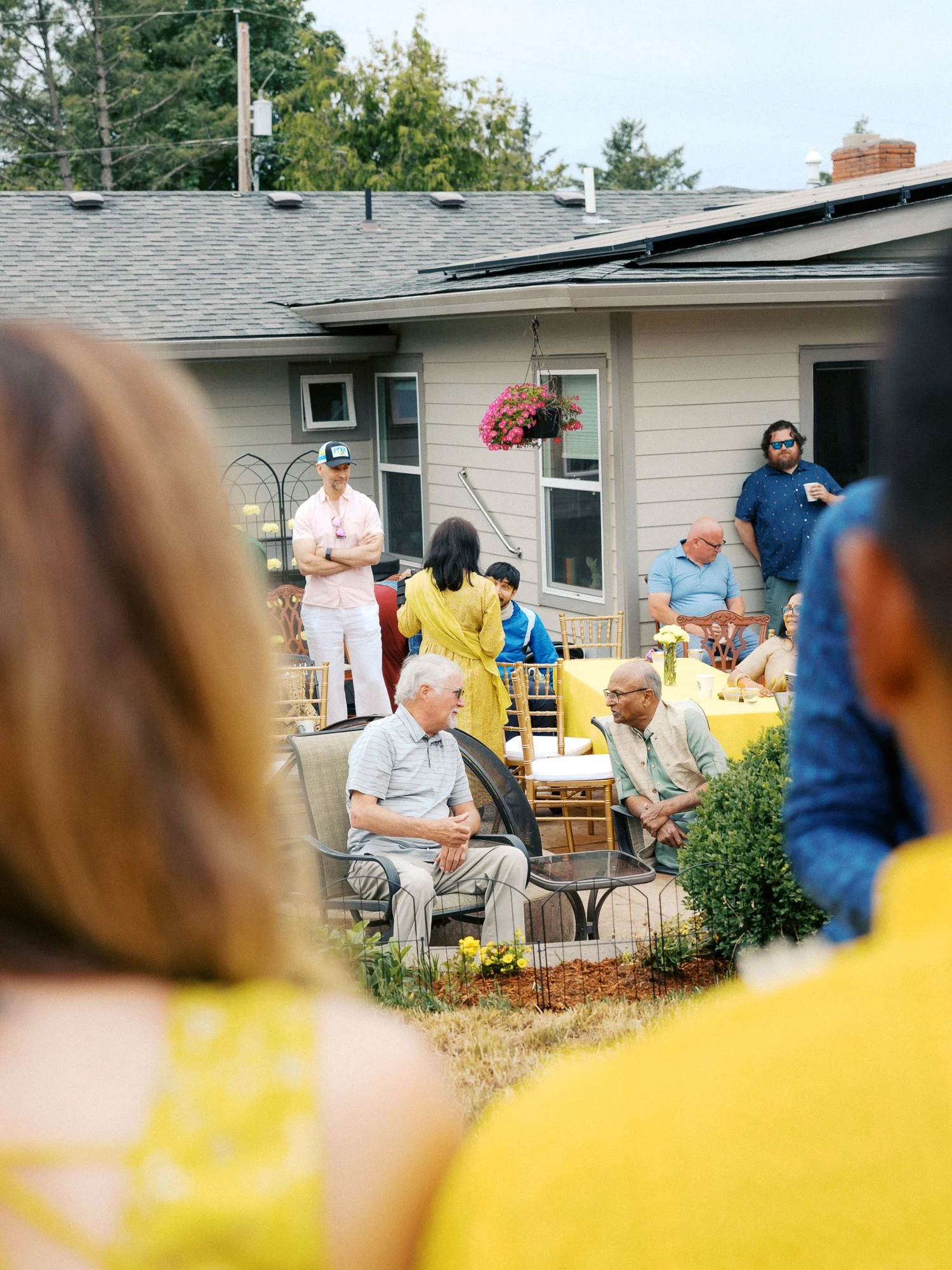 Family and friends mingle around yellow tables during the backyard Haldi celebration.