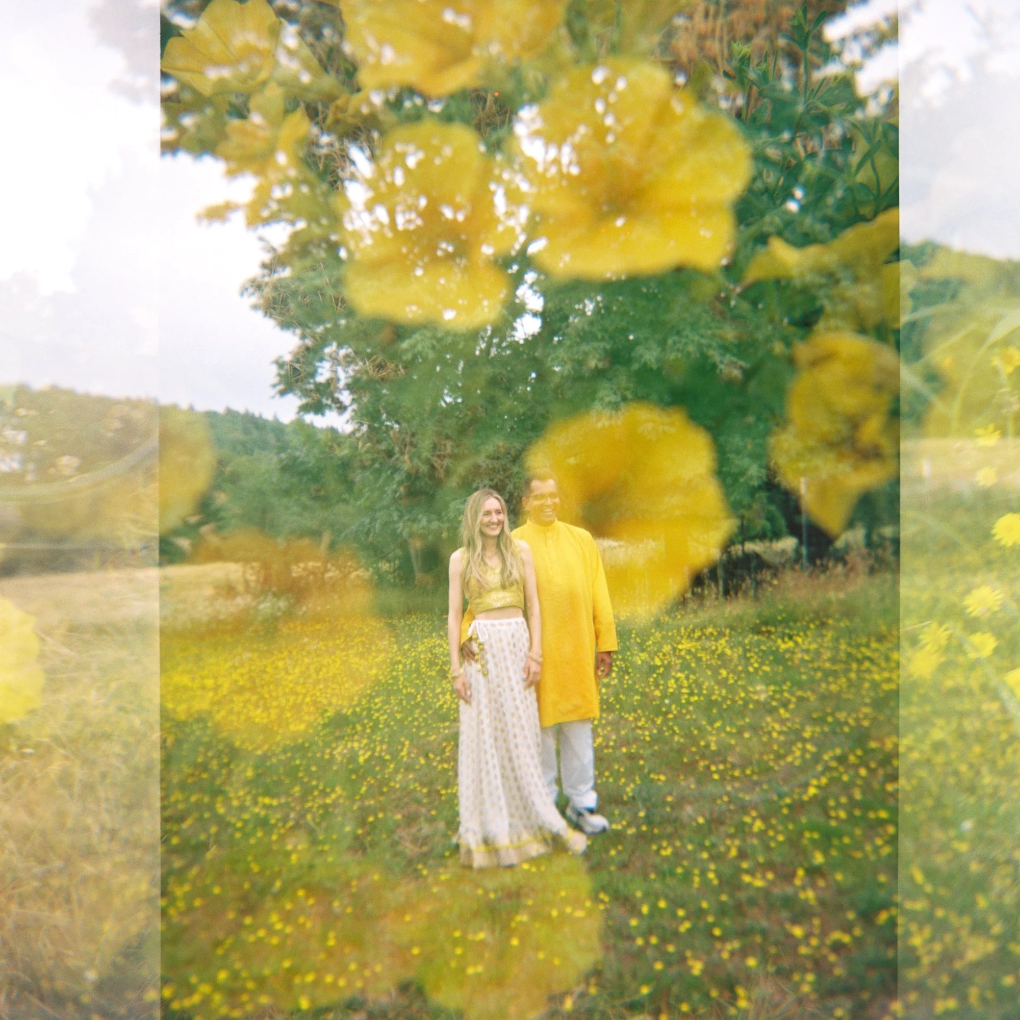 Artistic double-exposure portrait of Alacia and Rohit surrounded by yellow flowers during their Haldi celebration.